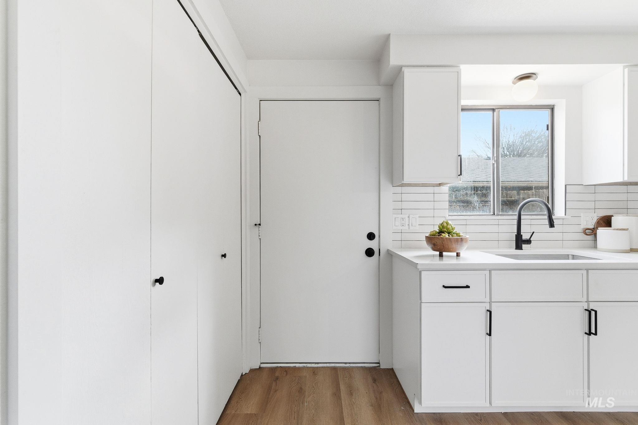 Kitchen with white cabinetry, light wood-type flooring, and tasteful backsplash
