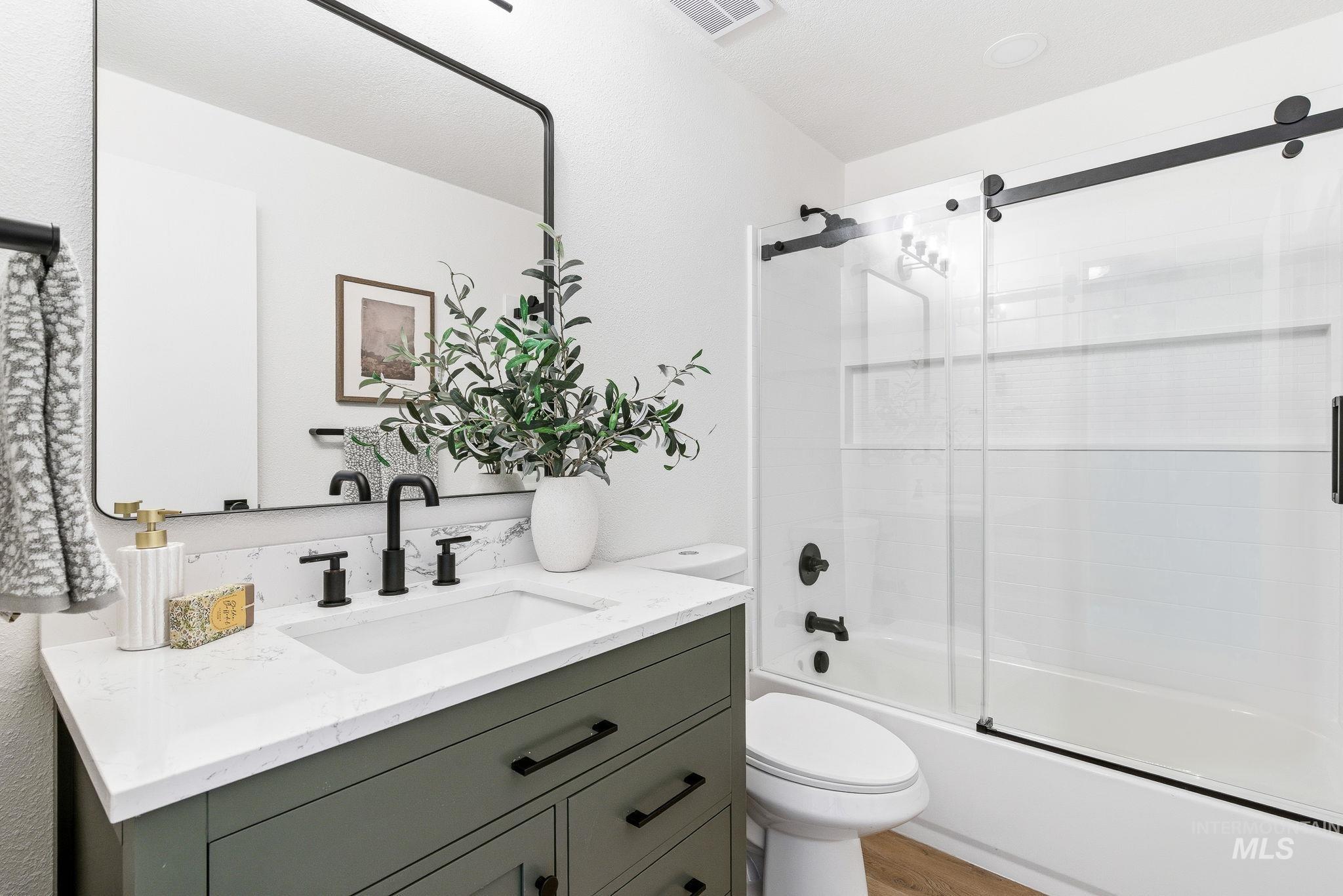 Full bath featuring bath / shower combo with glass door and vanity