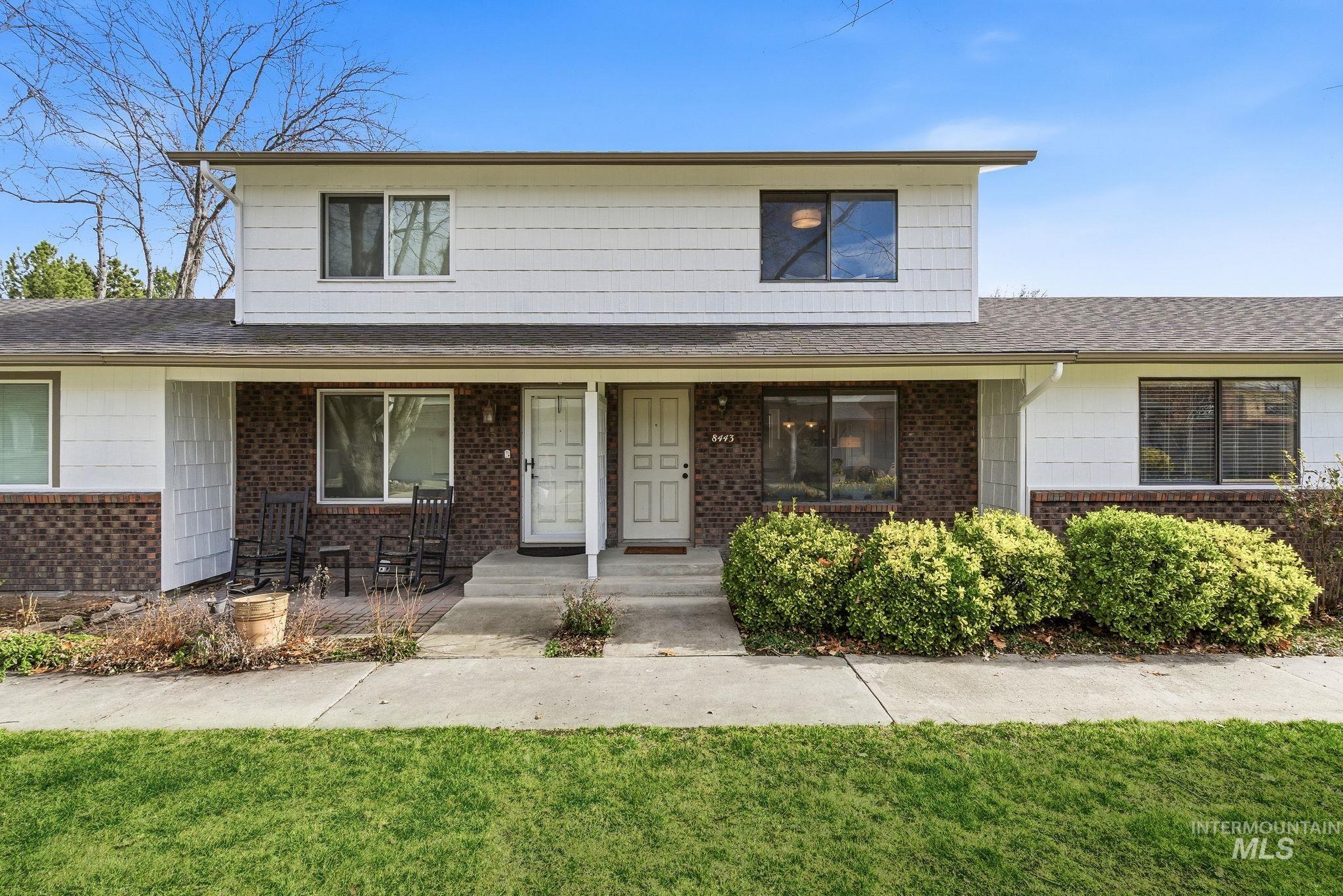 Traditional-style house with a front lawn, a porch, roof with shingles, and brick siding
