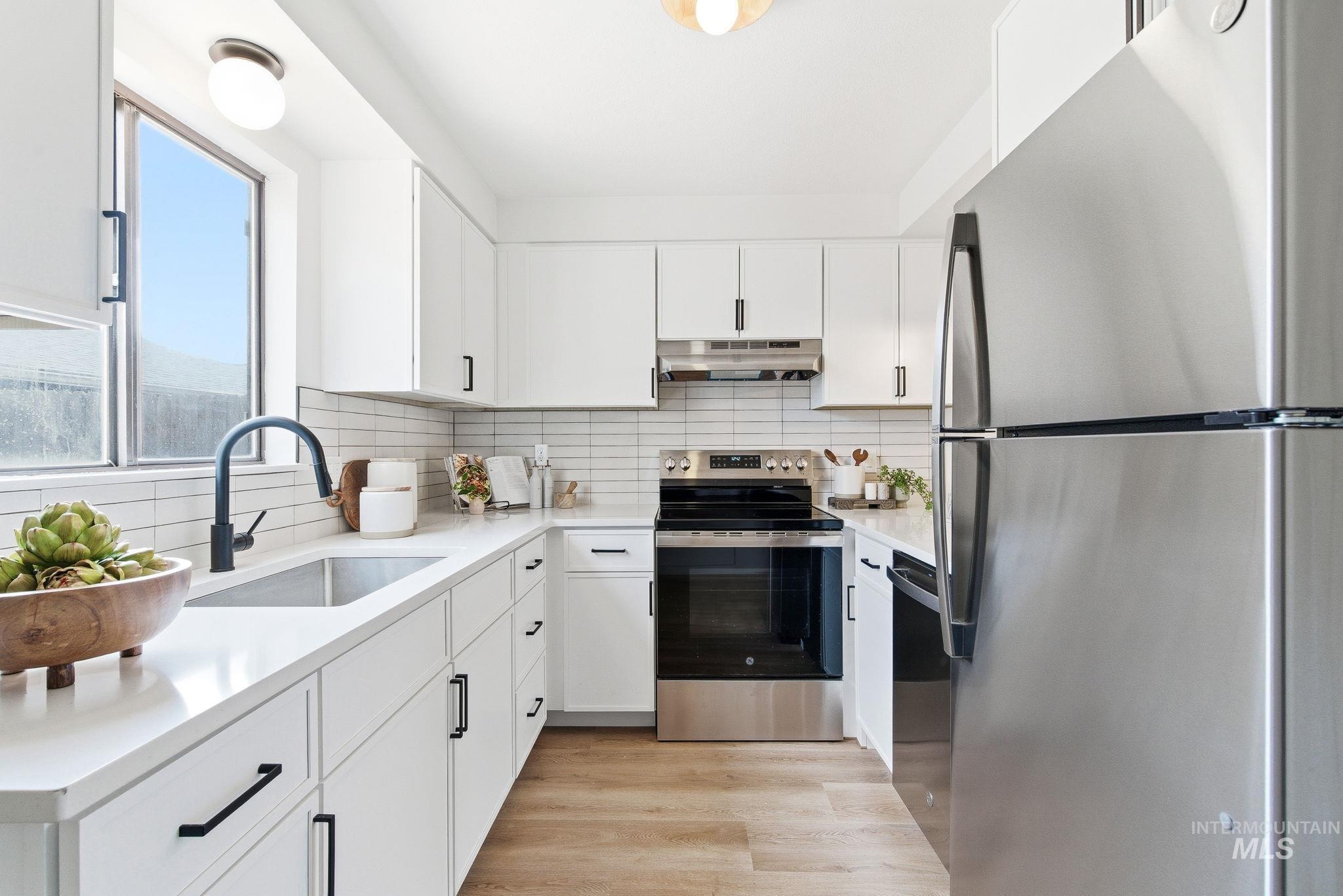 Kitchen featuring stainless steel appliances, white cabinets, and tasteful backsplash