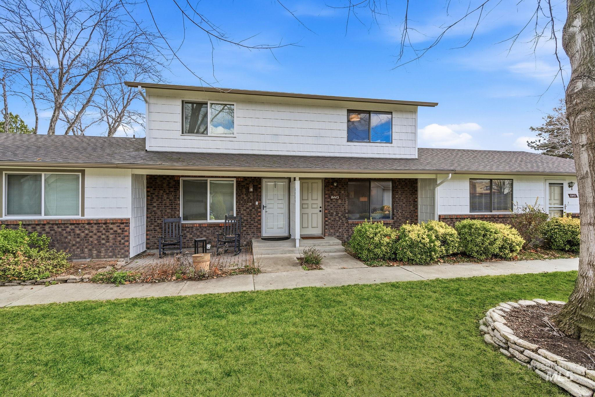 Traditional-style home featuring a front lawn, covered porch, a shingled roof, and brick siding