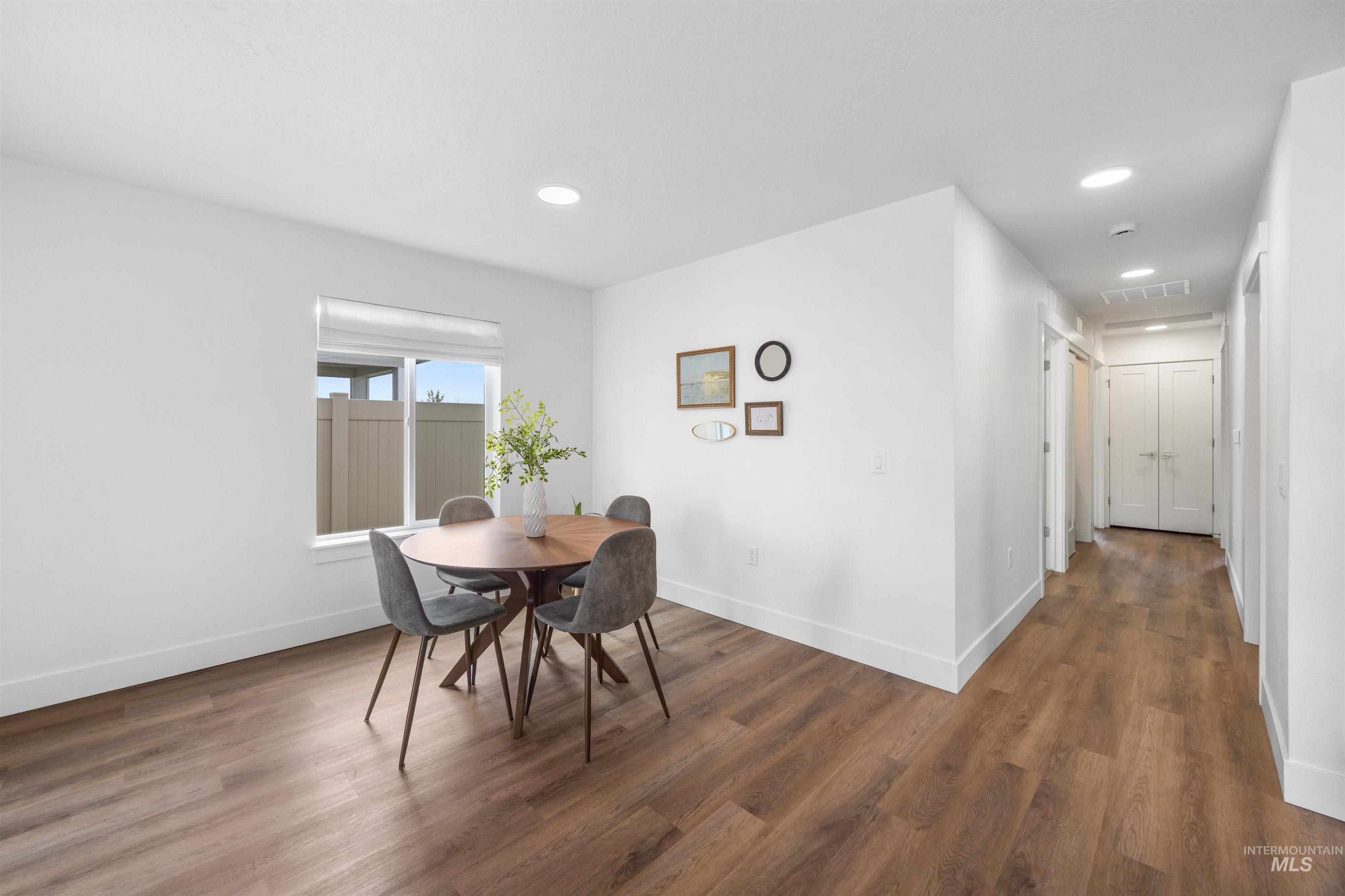 Bright dining area featuring wood-finish flooring, recessed lighting, and a large window with privacy blinds