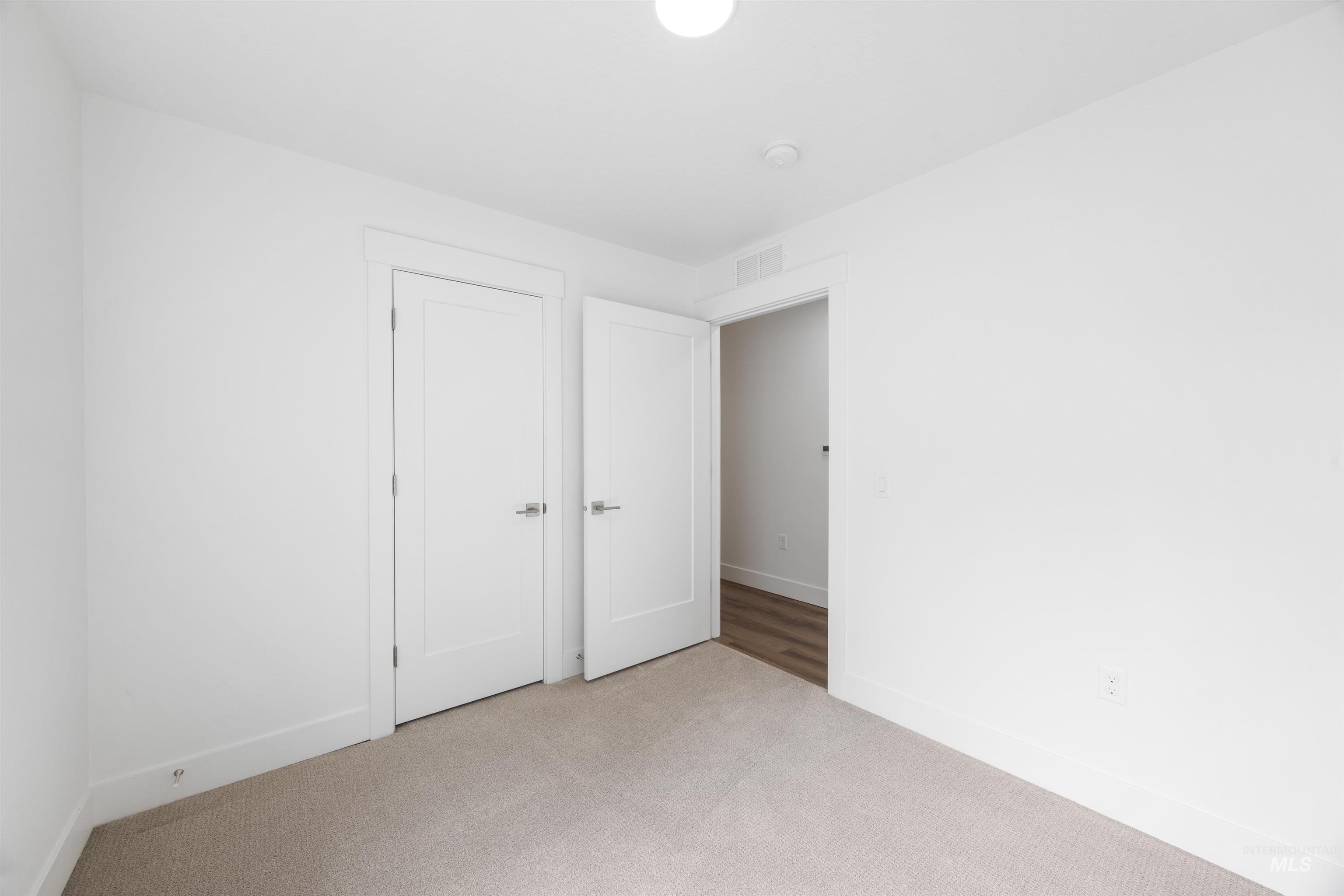 Neutral-toned carpet flooring and white painted walls with matching baseboards