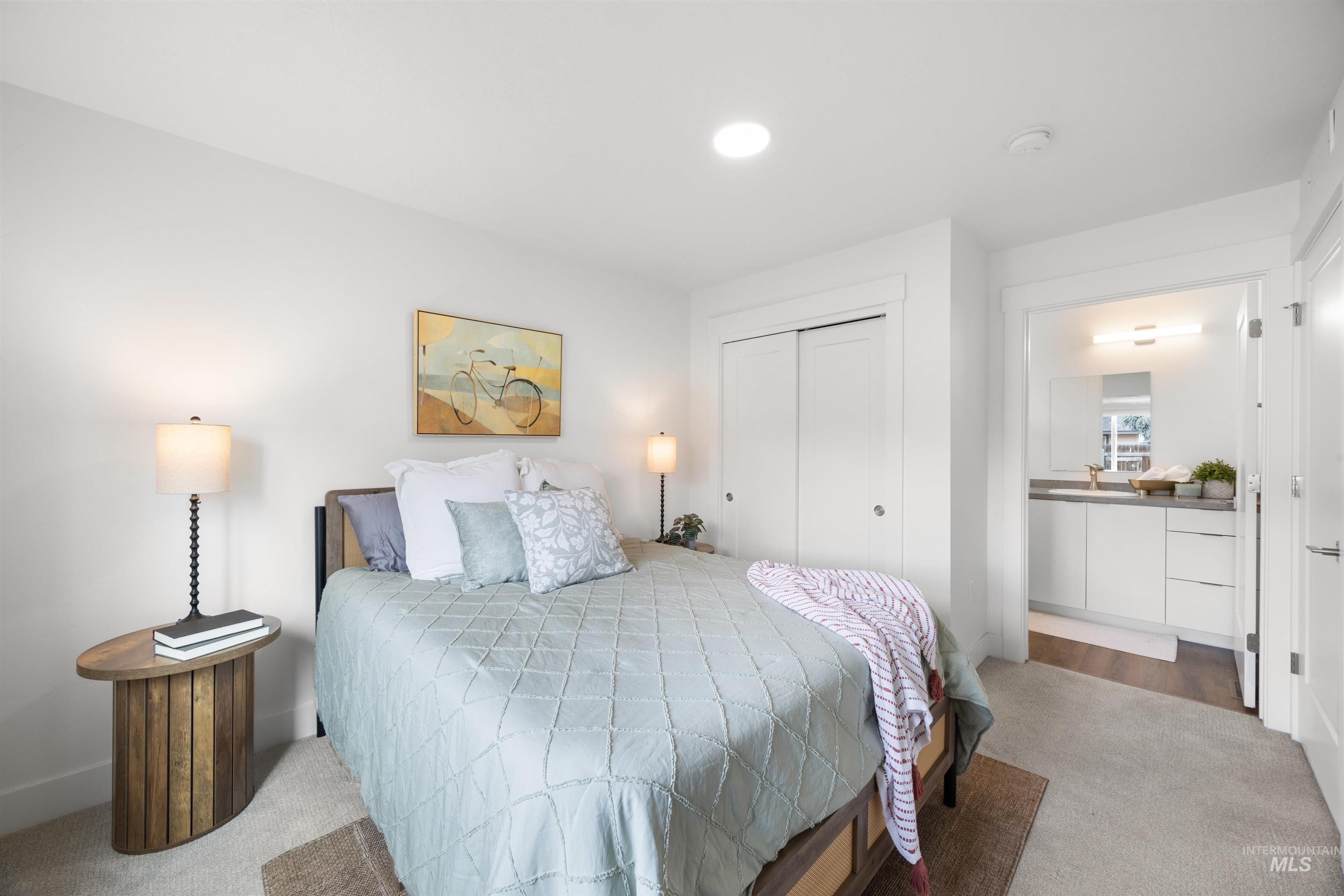 Carpeted sleeping area with recessed ceiling lighting, a built-in closet with sliding doors, and direct access to a private bathroom