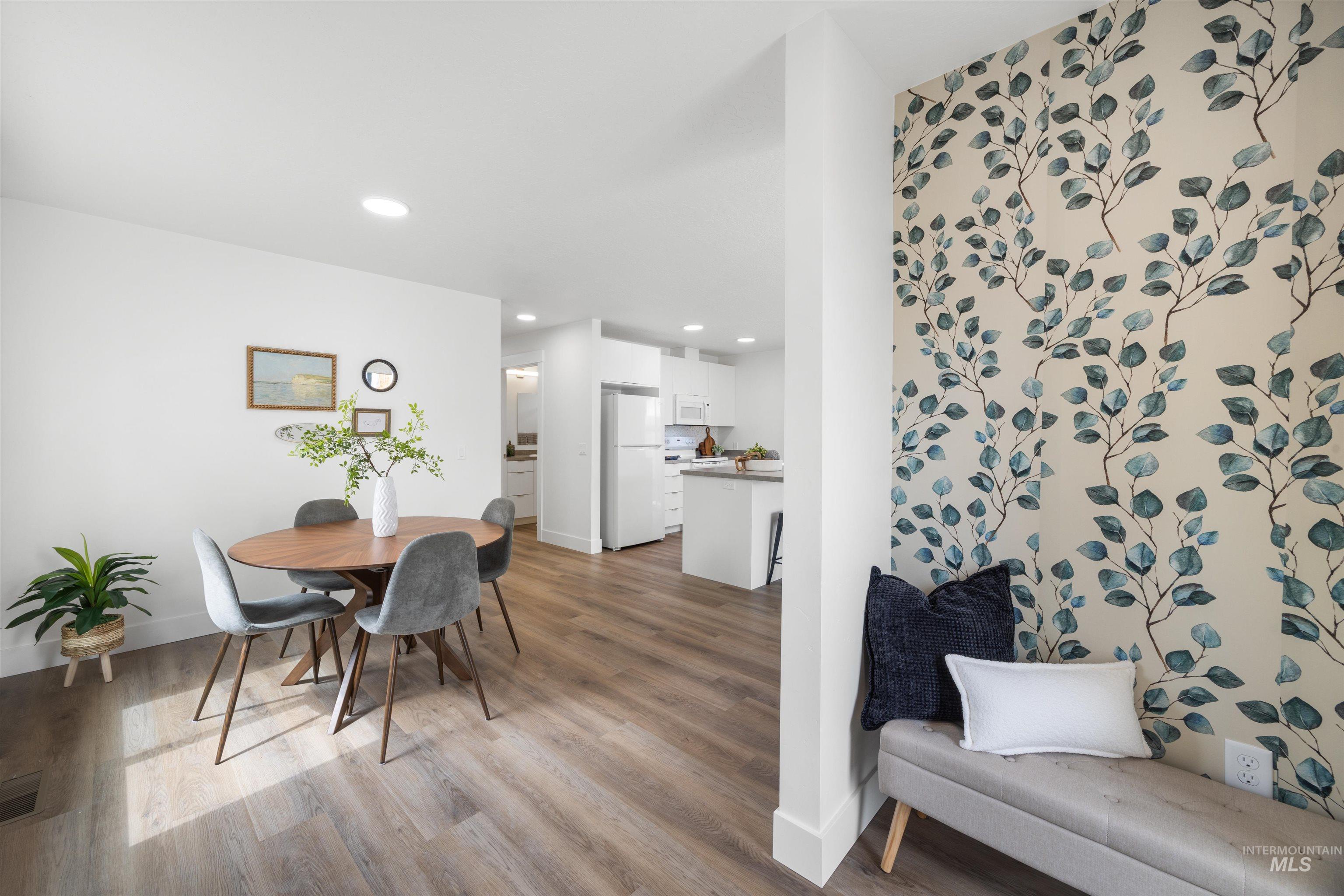 Dining area featuring wood-finish flooring, recessed lighting, and a decorative botanical accent wall