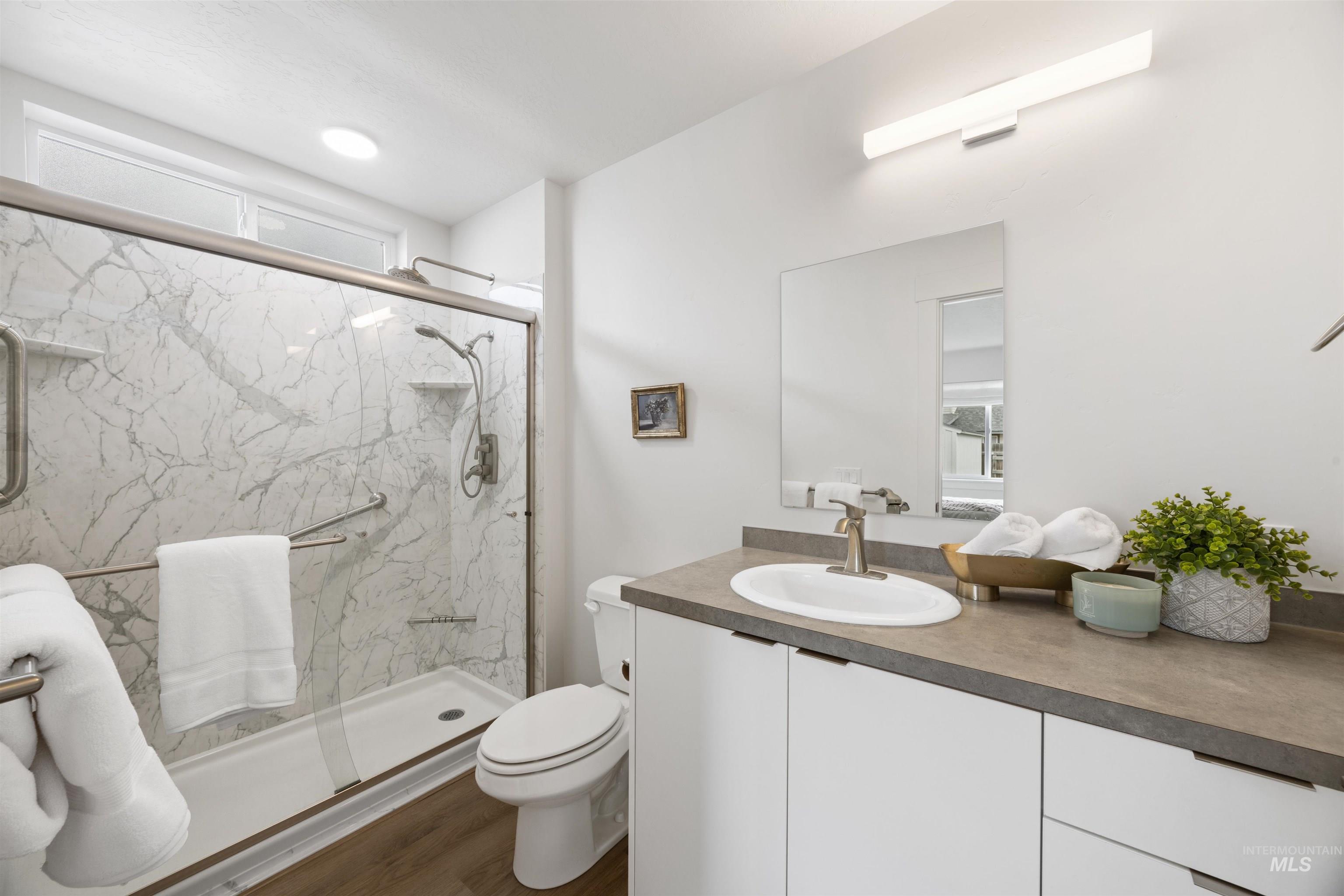 Bathroom featuring a shower with a sliding glass door and marble-look wall panels