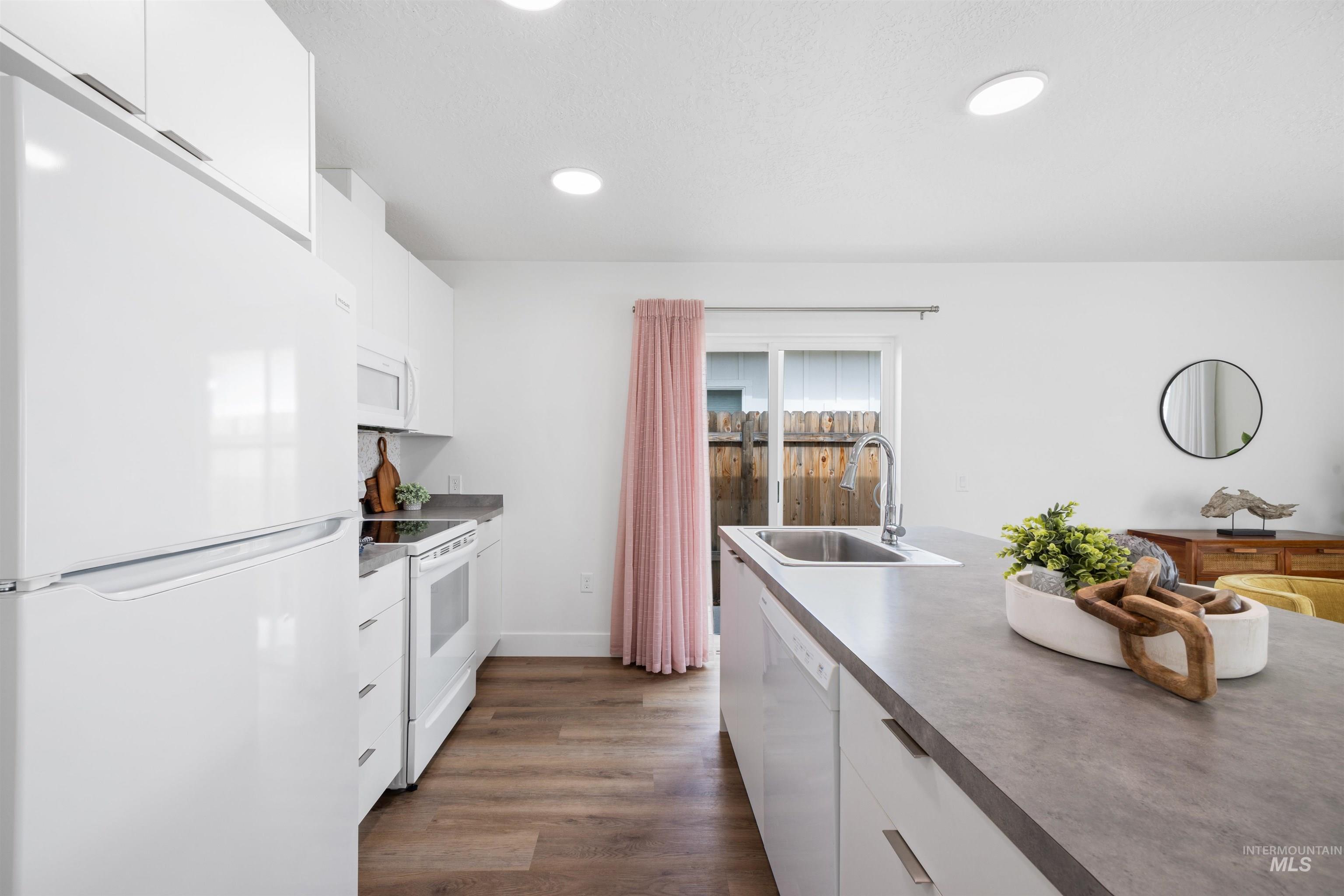 Kitchen with white cabinets, white appliances, dark wood-type flooring, recessed lighting, and dark countertops