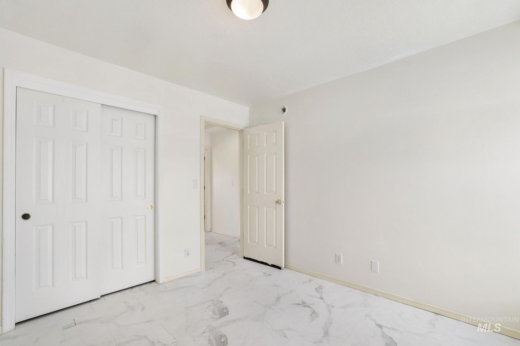 Unfurnished bedroom with a closet and marble look tile flooring