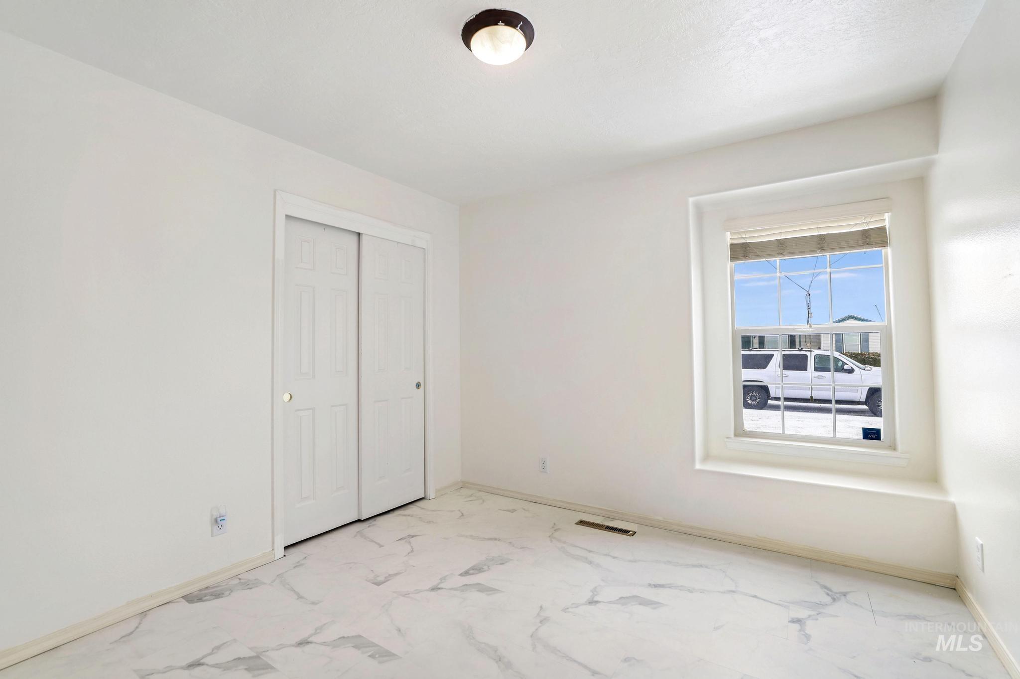 Unfurnished bedroom featuring a closet and marble look tiles