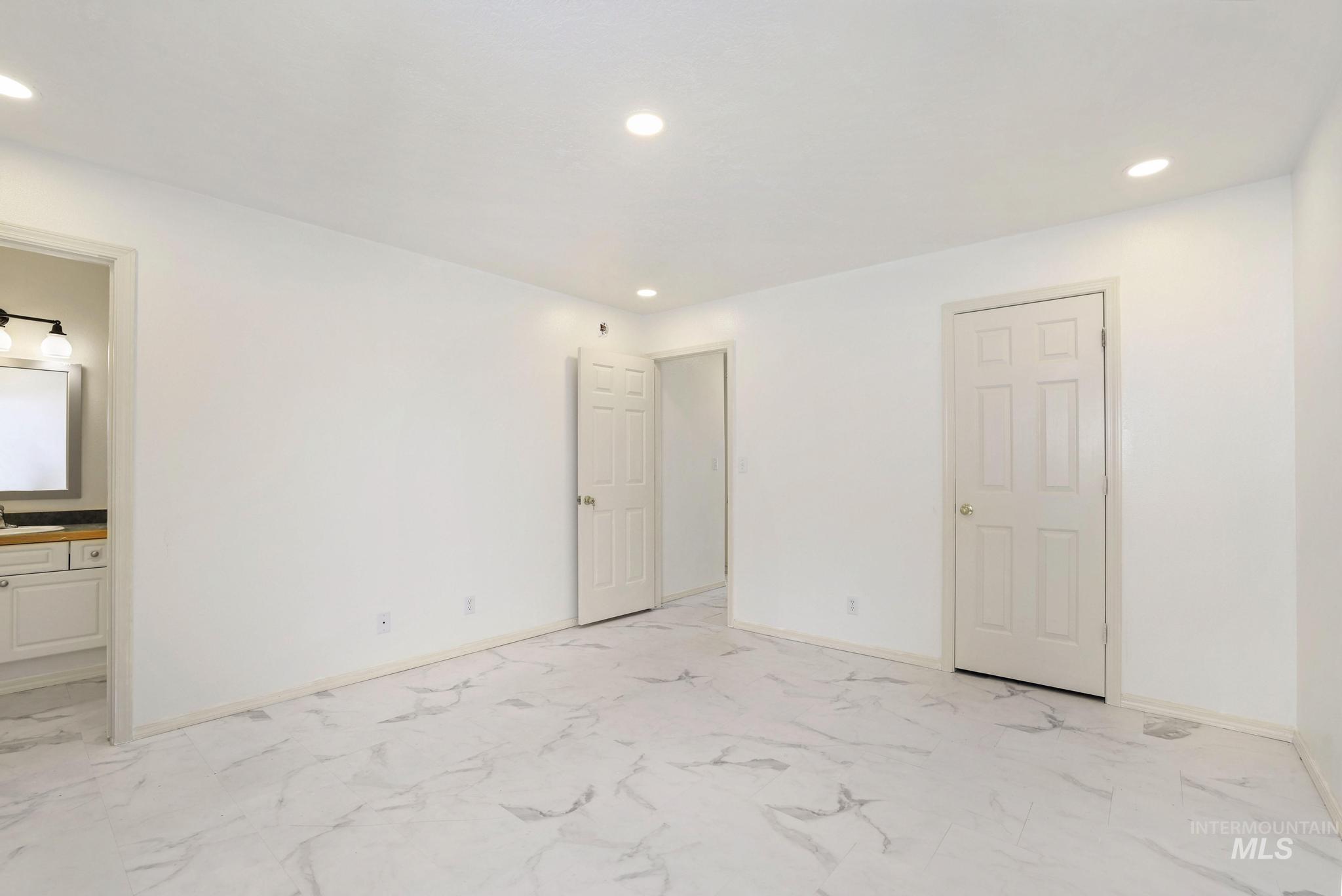 Unfurnished bedroom with recessed lighting, light marble finish floors, and connected bathroom