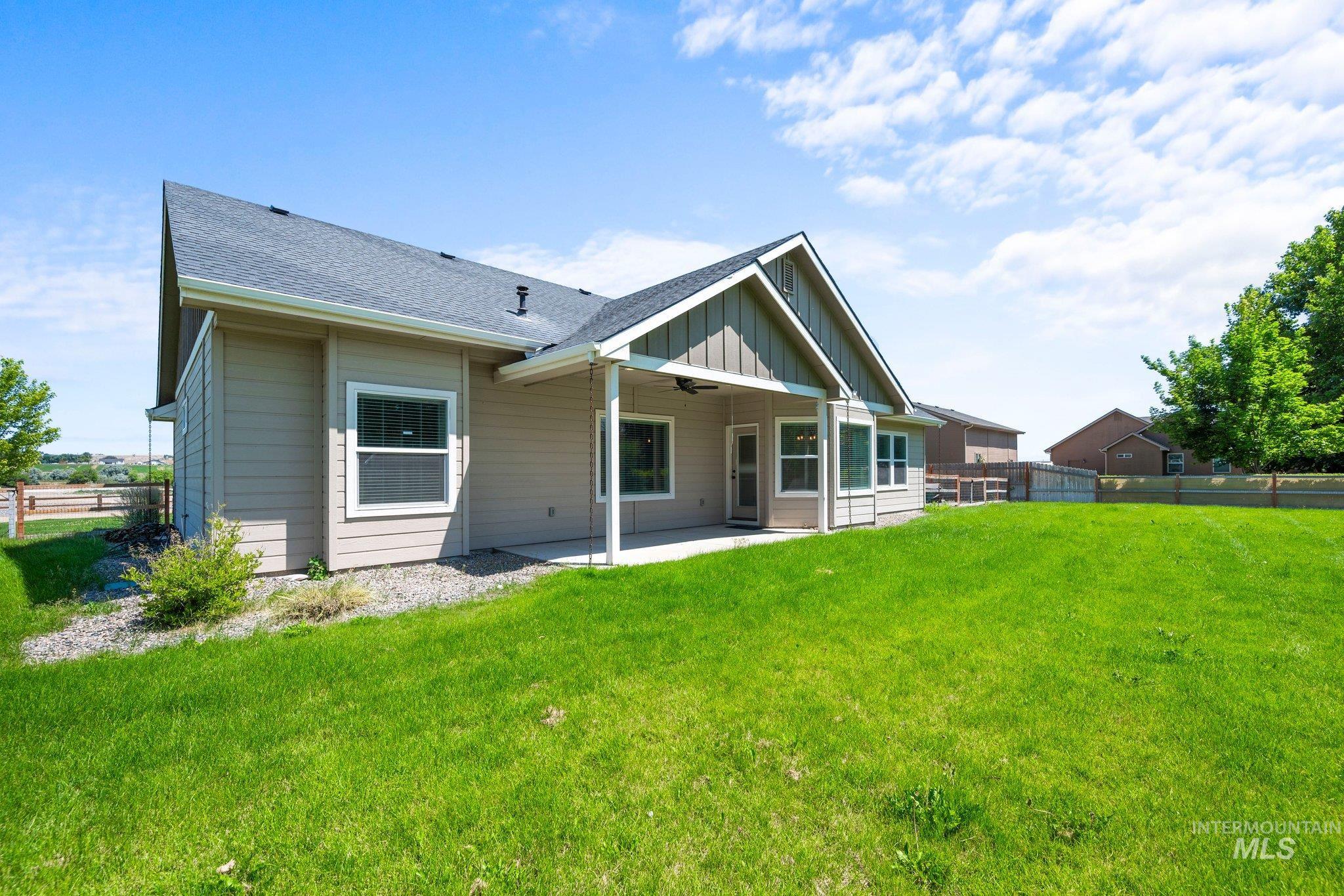 Back of house featuring board and batten siding, a patio, ceiling fan, and a shingled roof