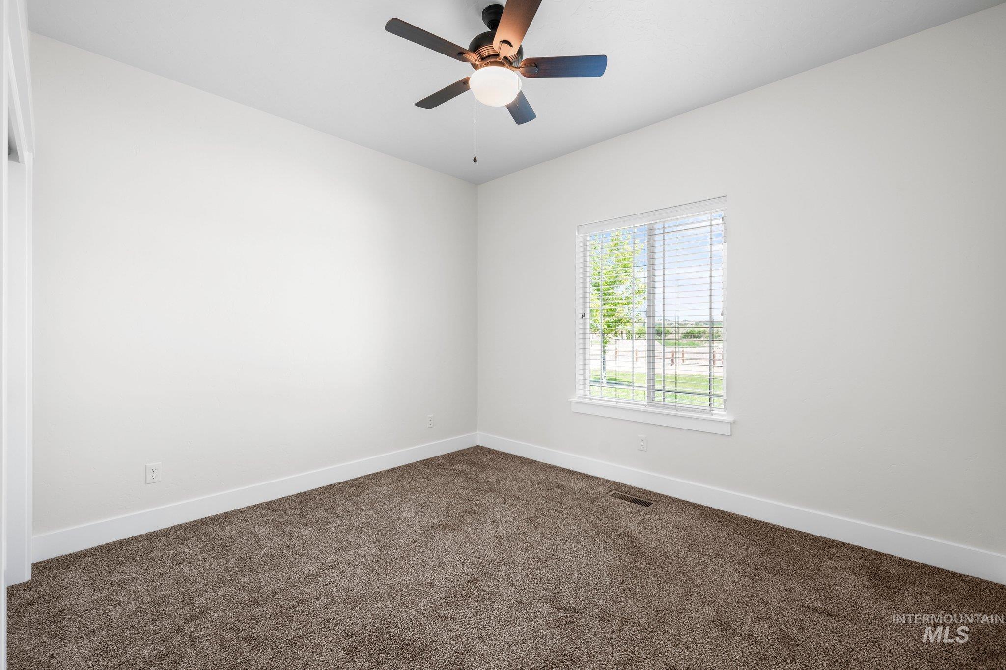 Empty room with dark carpet and a ceiling fan