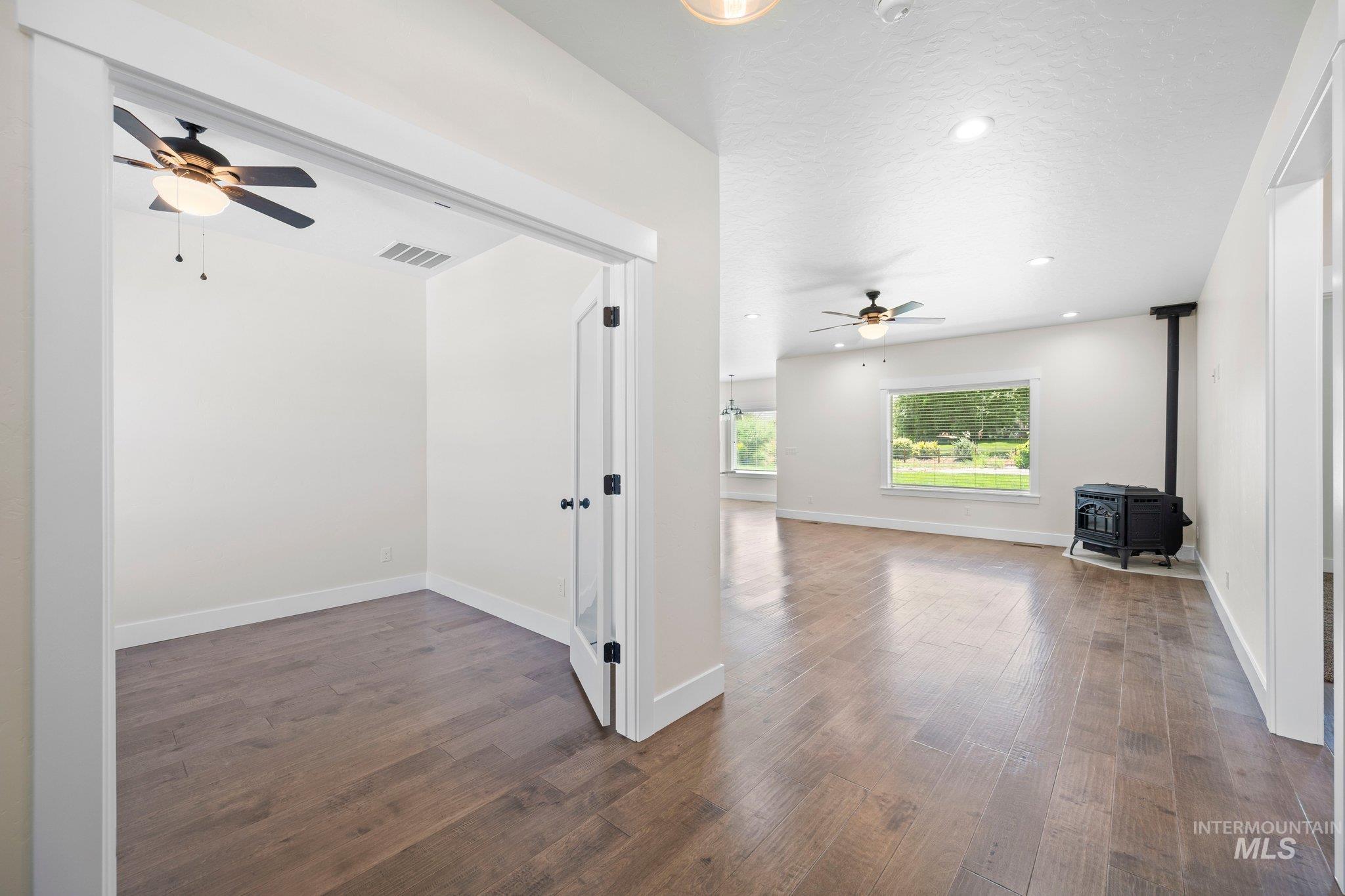 Empty room featuring a ceiling fan, a wood stove, wood finished floors, and recessed lighting