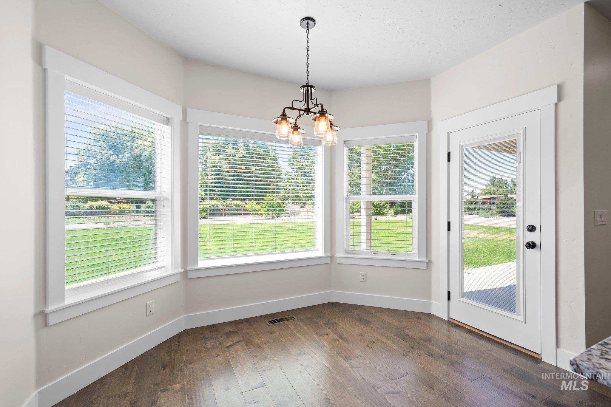 Unfurnished dining area with a chandelier, dark wood-type flooring, and plenty of natural light