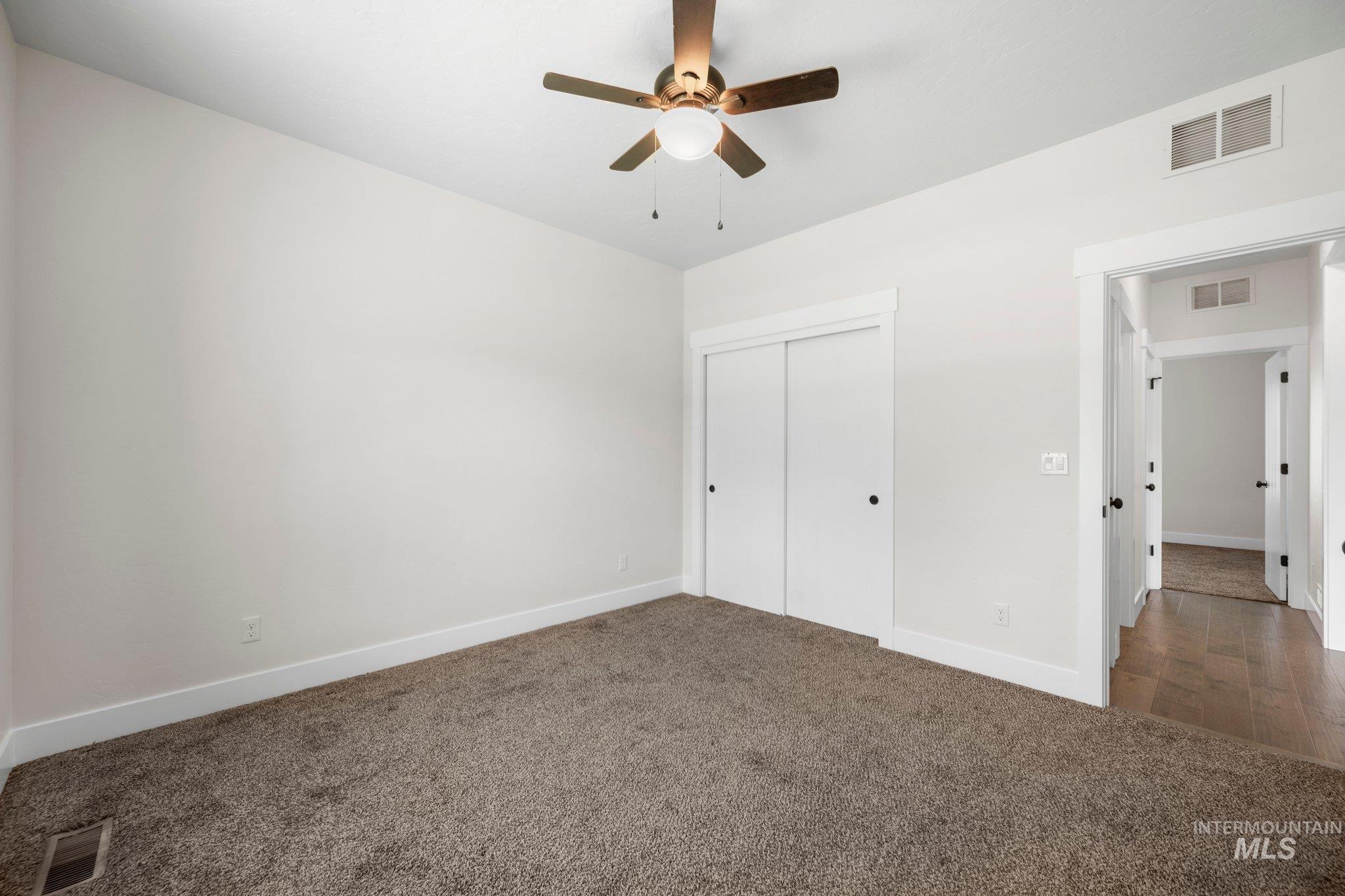 Unfurnished bedroom with carpet, a closet, and a ceiling fan
