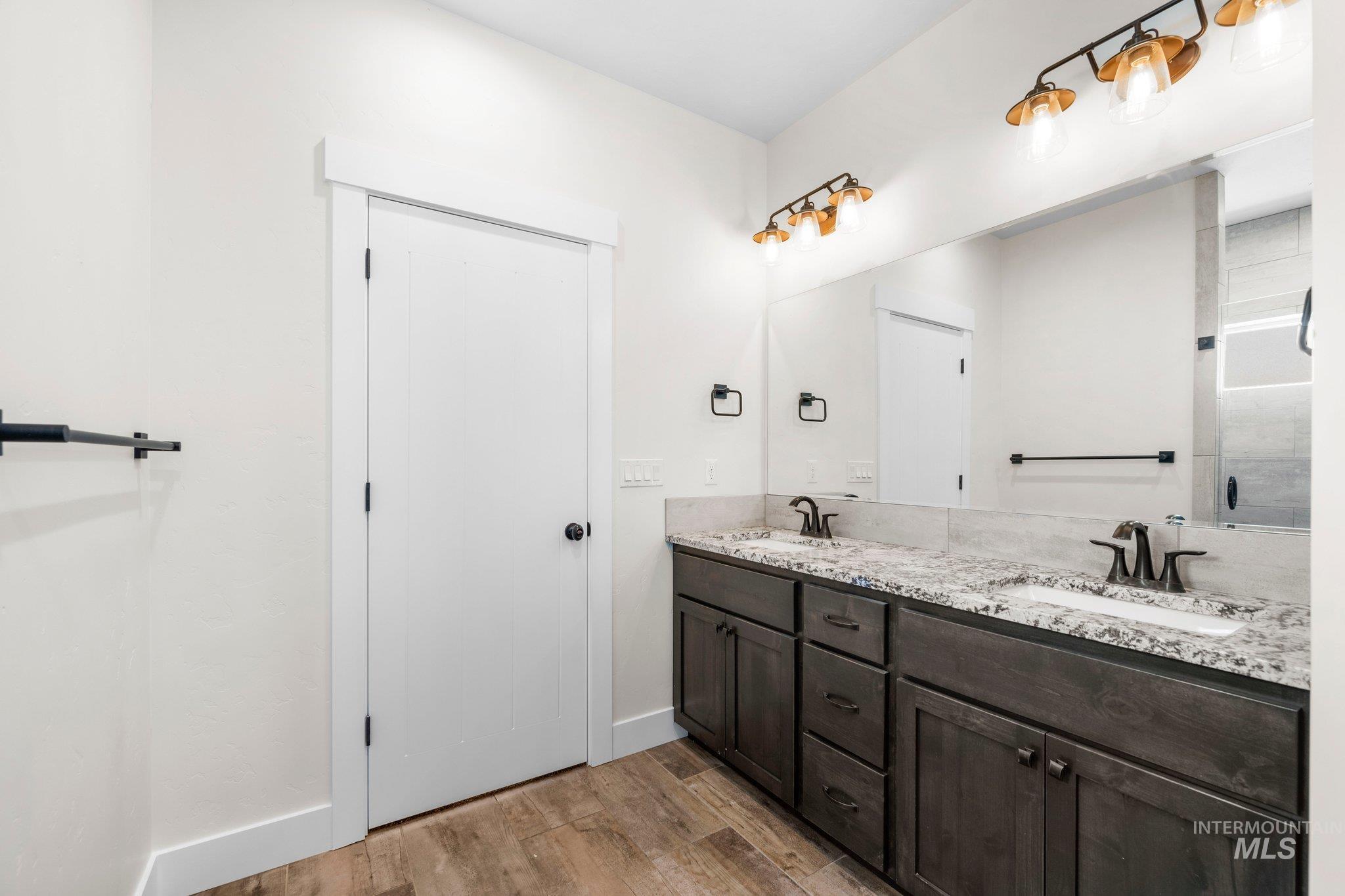 Full bath featuring double vanity and wood finished floors