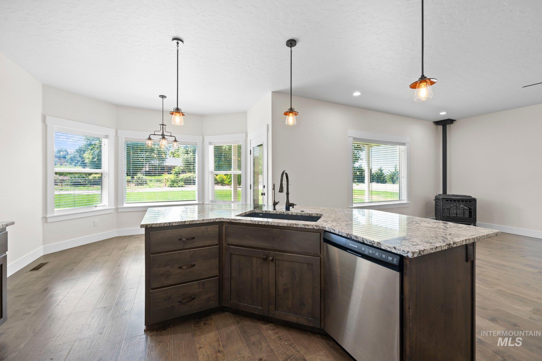 Kitchen featuring stainless steel dishwasher, a wood stove, dark wood finished floors, dark brown cabinets, and recessed lighting