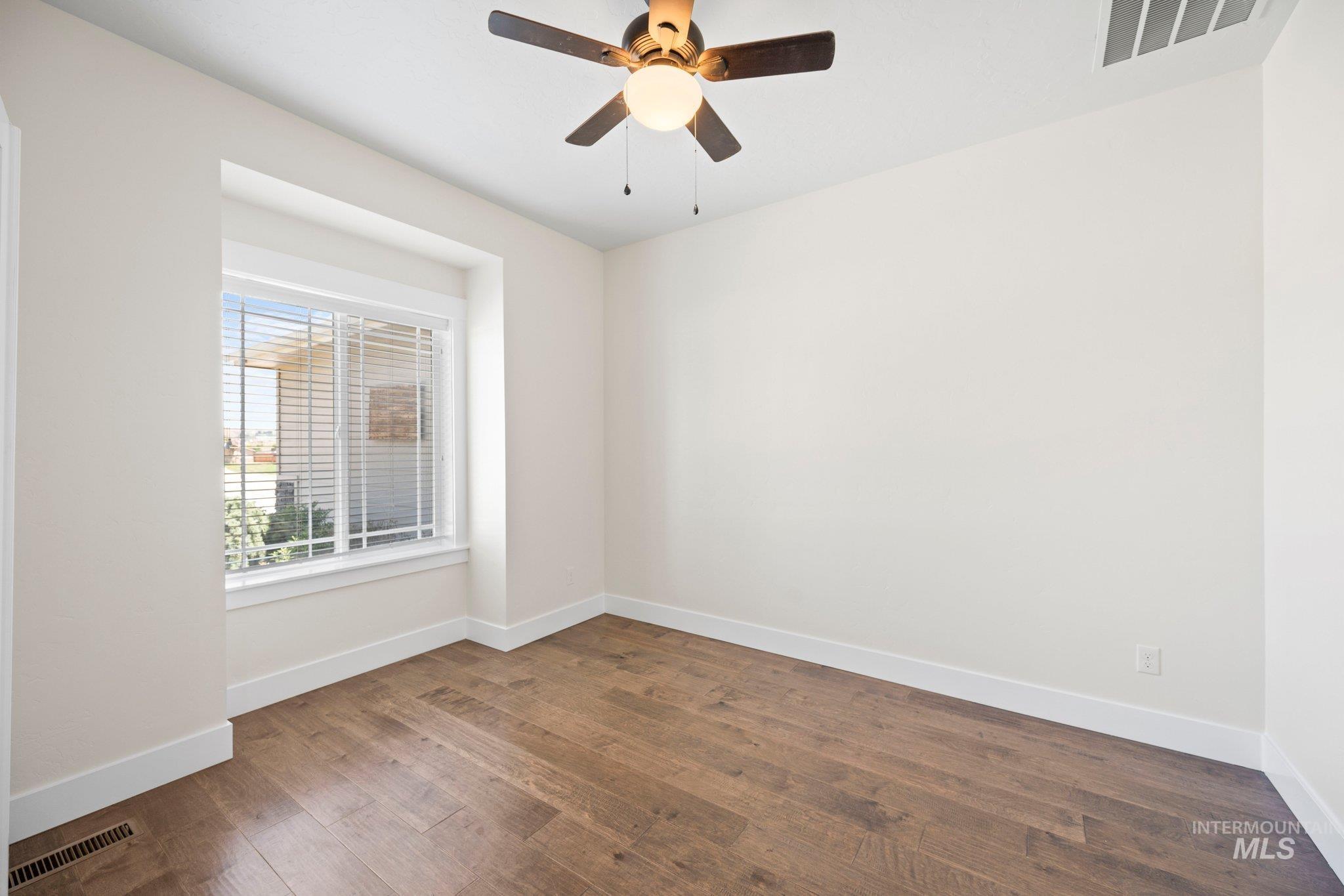 Empty room with wood finished floors and ceiling fan