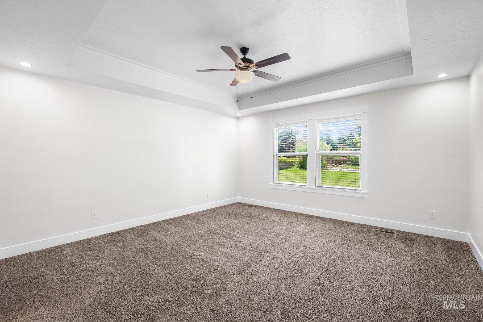 Unfurnished room with a raised ceiling, ornamental molding, ceiling fan, carpet floors, and recessed lighting