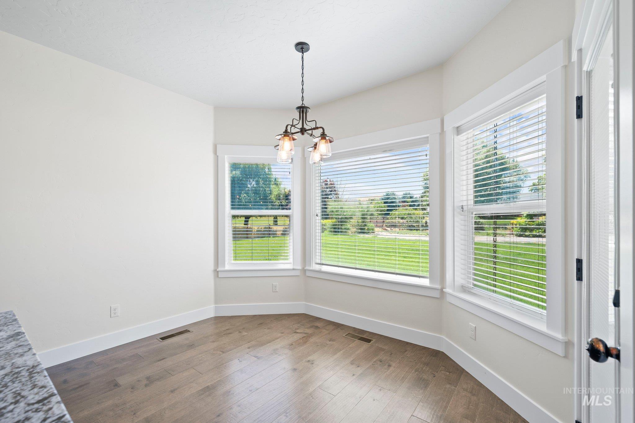 Unfurnished dining area featuring a chandelier and hardwood / wood-style flooring