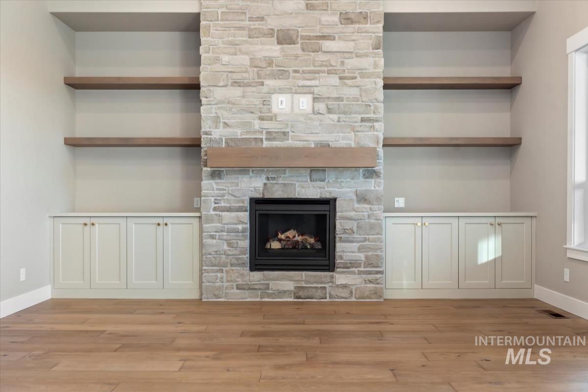 Unfurnished living room with built in features, a fireplace, and light wood-type flooring