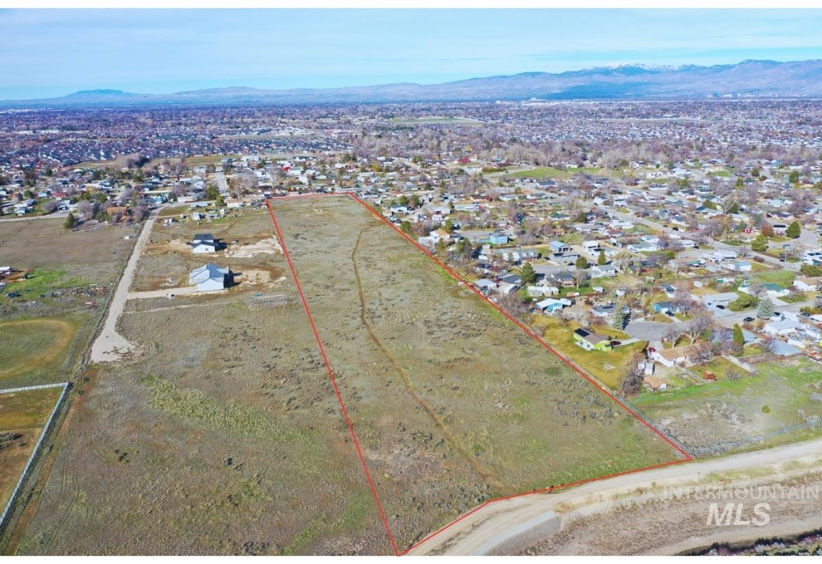 Aerial view of residential area with property parcel outlined and mountains