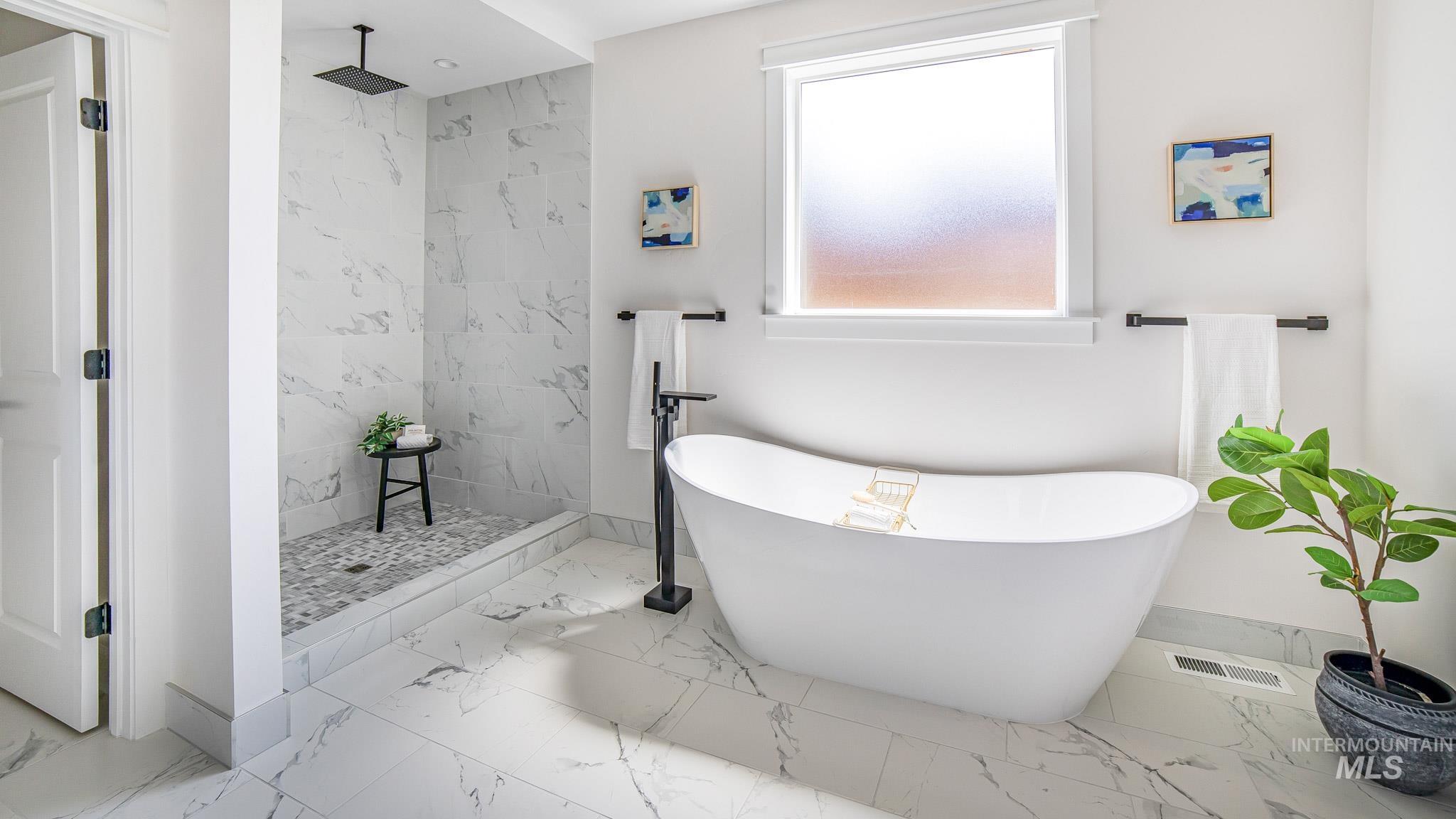 Full bath featuring marble finish floors, a soaking tub, and walk in shower