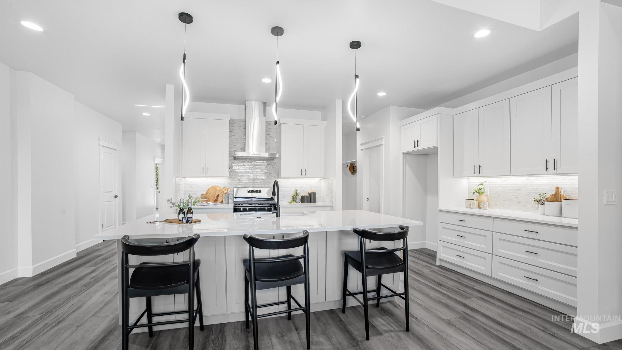 Kitchen with wall chimney range hood, white cabinets, light countertops, wood finished floors, and recessed lighting