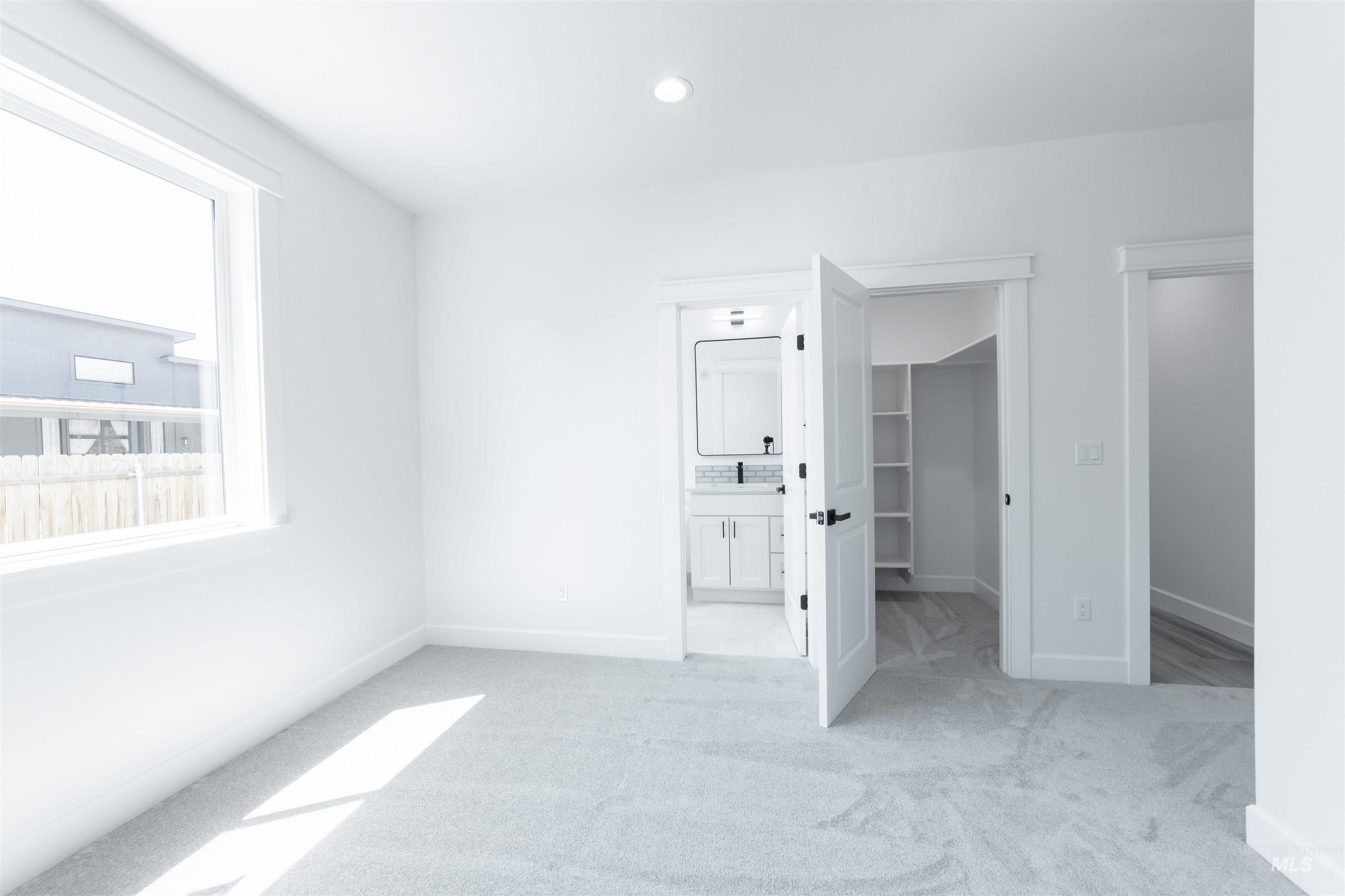 Unfurnished bedroom with carpet, a spacious closet, recessed lighting, and ensuite bathroom