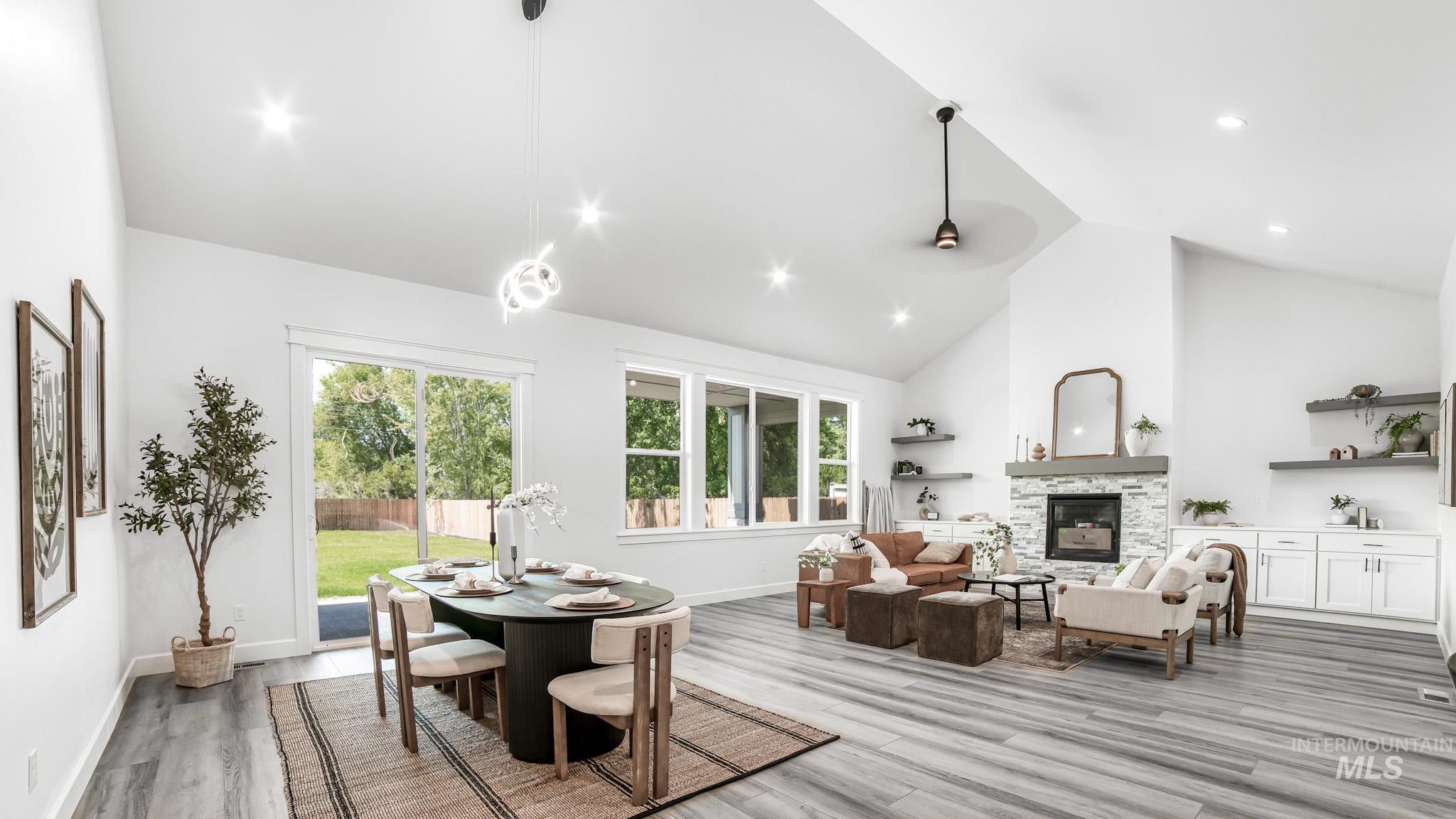 Dining room featuring light wood-style flooring, recessed lighting, high vaulted ceiling, and a fireplace