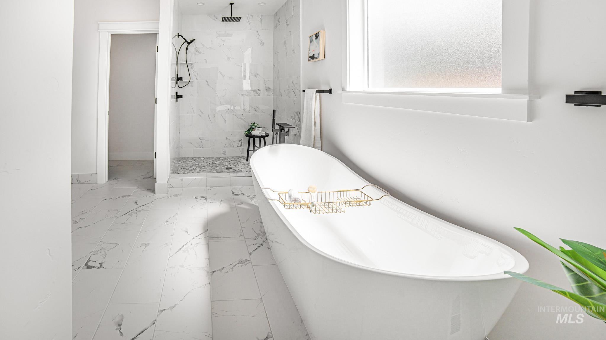 Full bath featuring marble look tiles, a marble finish shower, and a freestanding bath