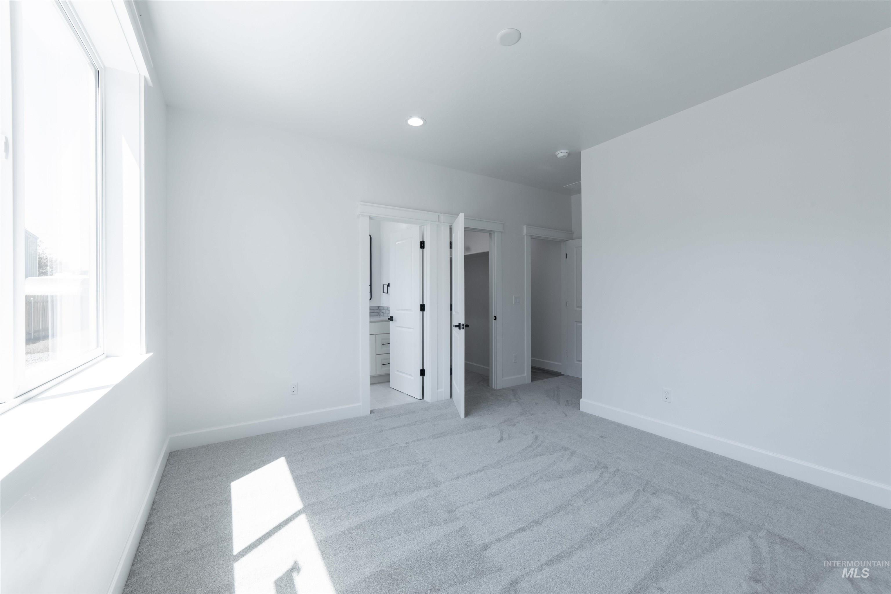 Unfurnished bedroom with light colored carpet, recessed lighting, and connected bathroom