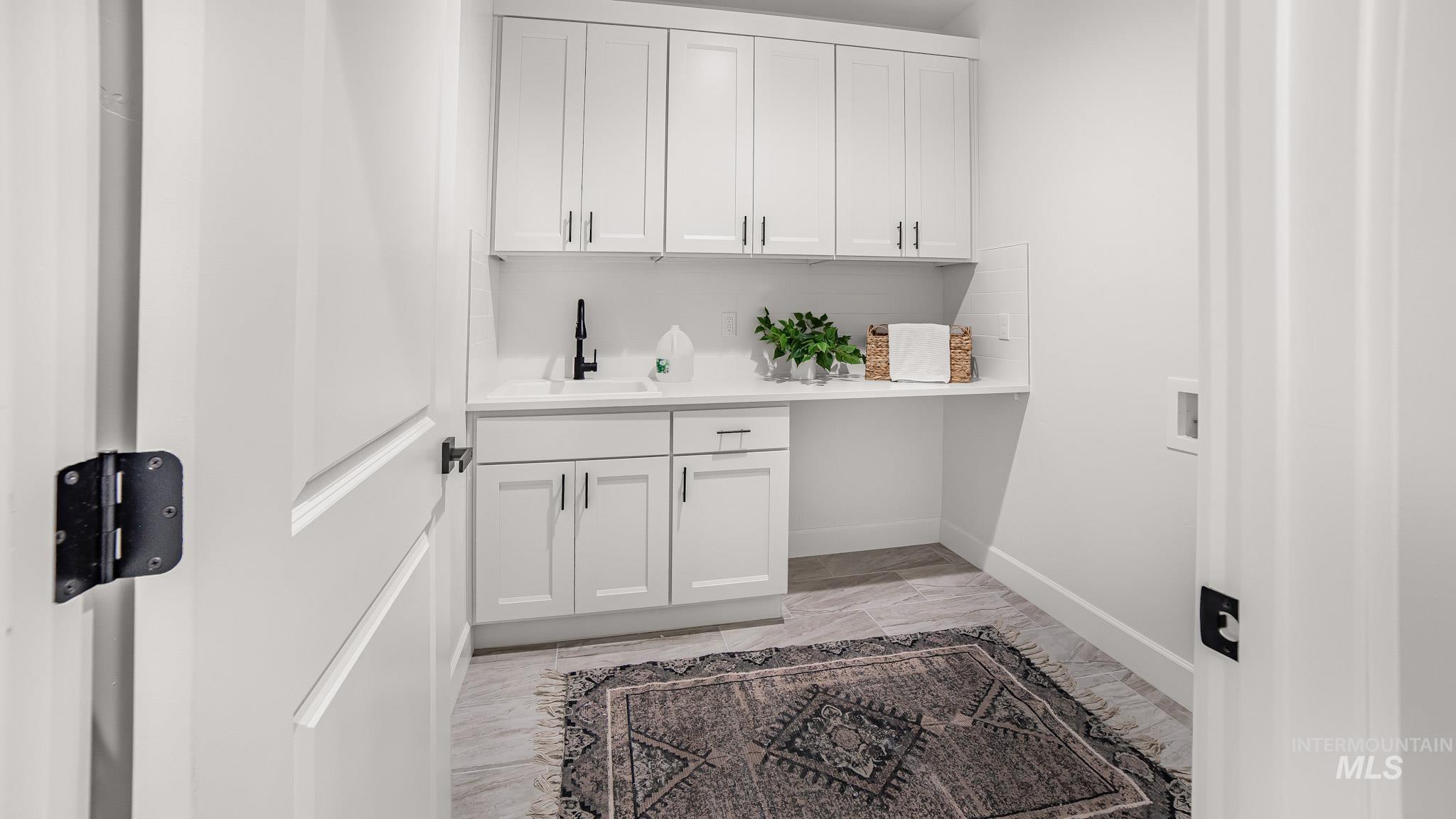 Laundry room featuring hookup for a washing machine, cabinet space, and light marble finish flooring