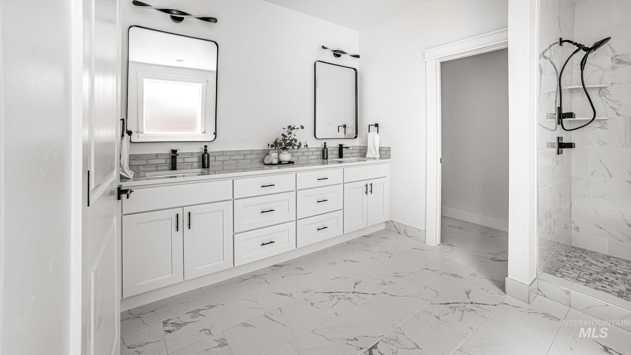 Bathroom featuring marble finish floors, double vanity, and a marble finish shower