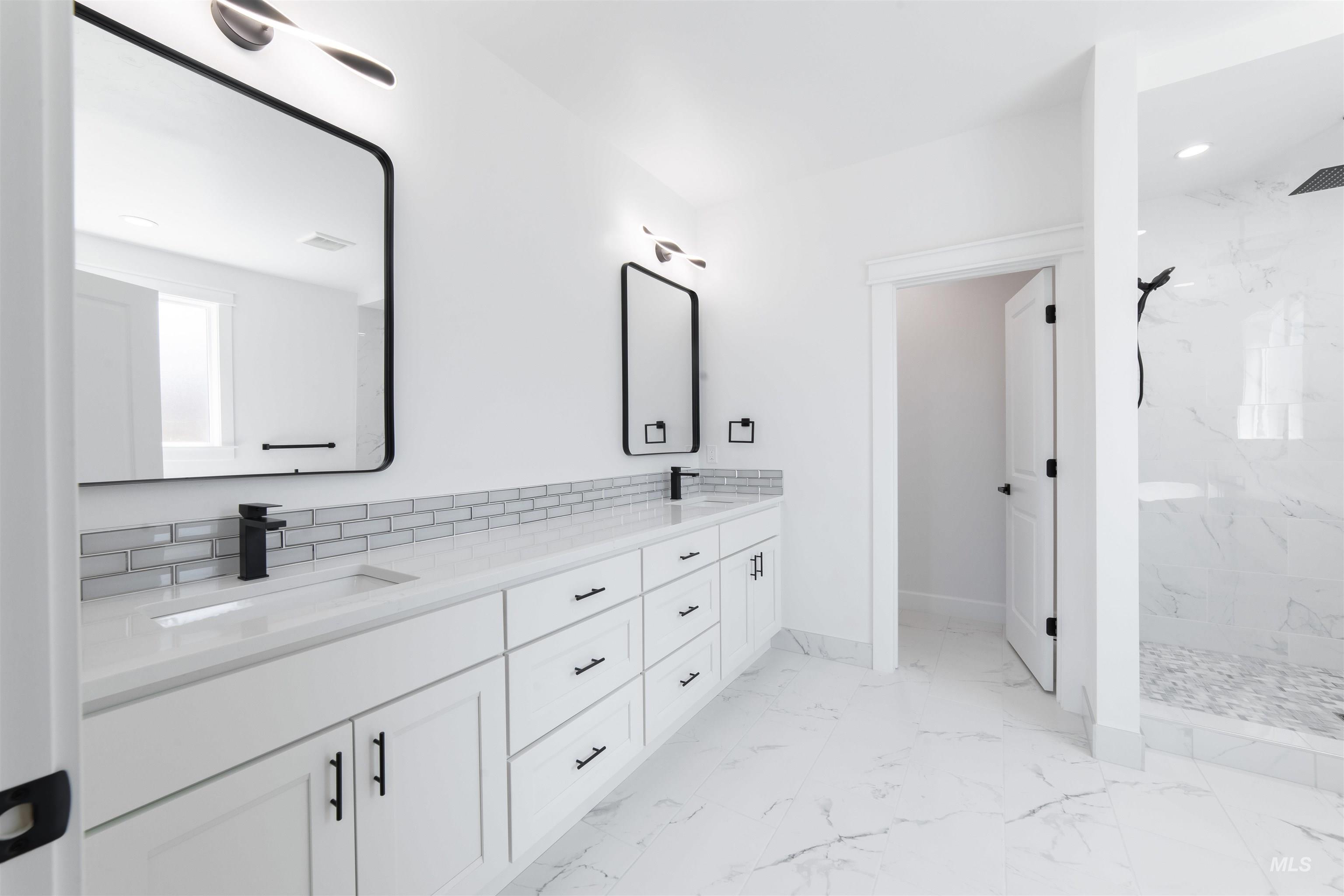 Full bathroom featuring marble look tile flooring, double vanity, a marble finish shower, and recessed lighting