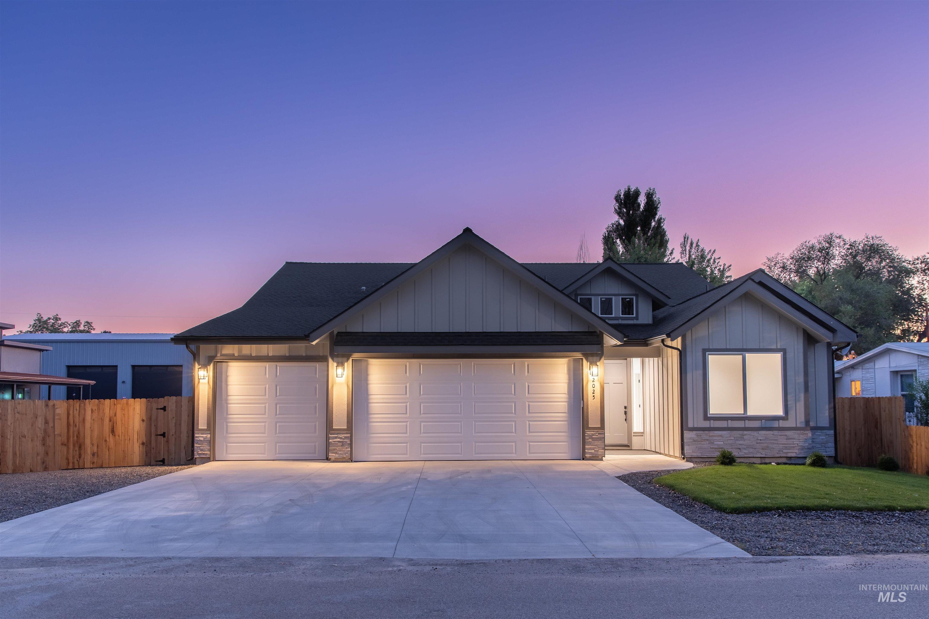 View of front facade with board and batten siding, an attached garage, concrete driveway, and stone siding