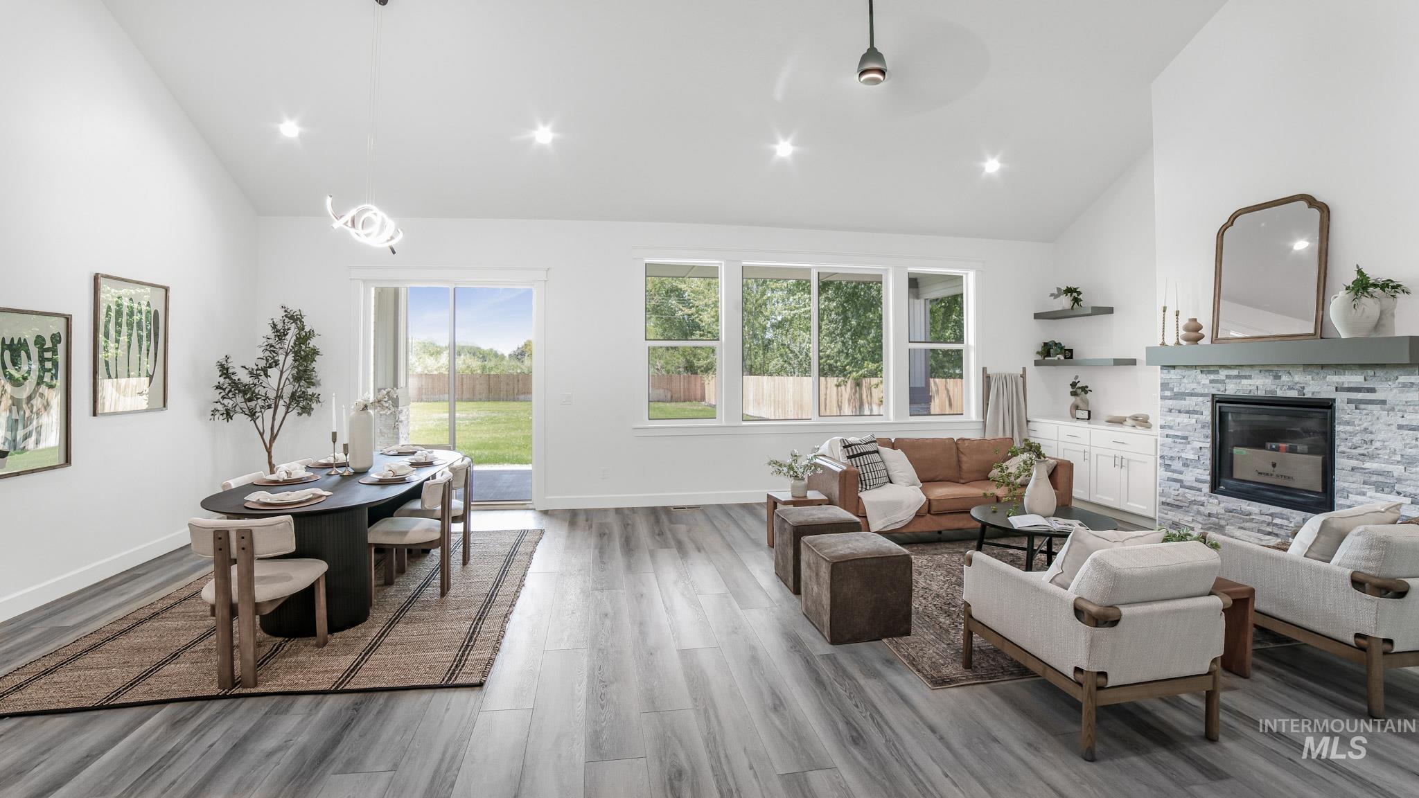 Living room featuring high vaulted ceiling, recessed lighting, wood finished floors, and a stone fireplace