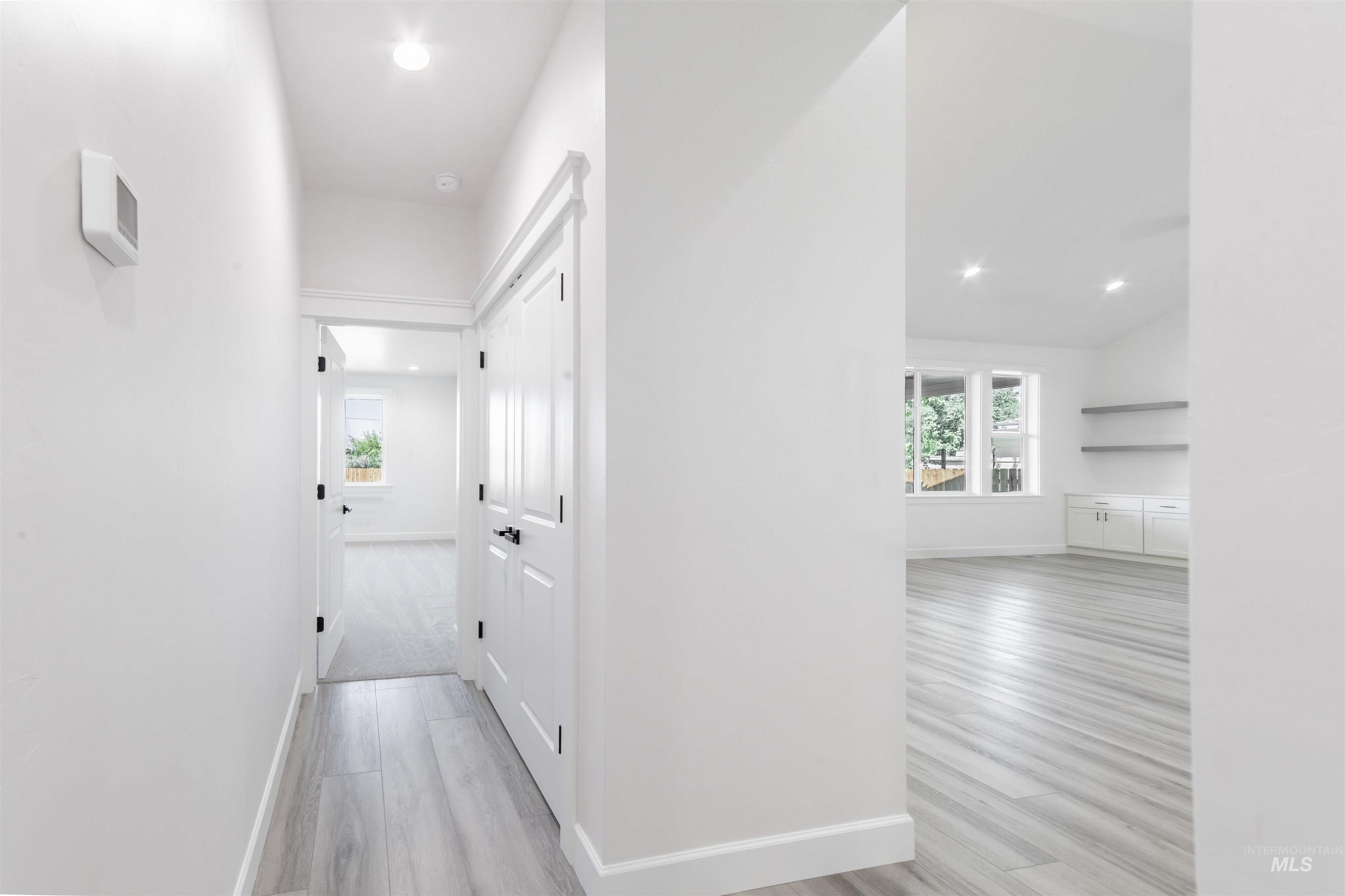 Hall with wood finished floors, plenty of natural light, recessed lighting, and lofted ceiling