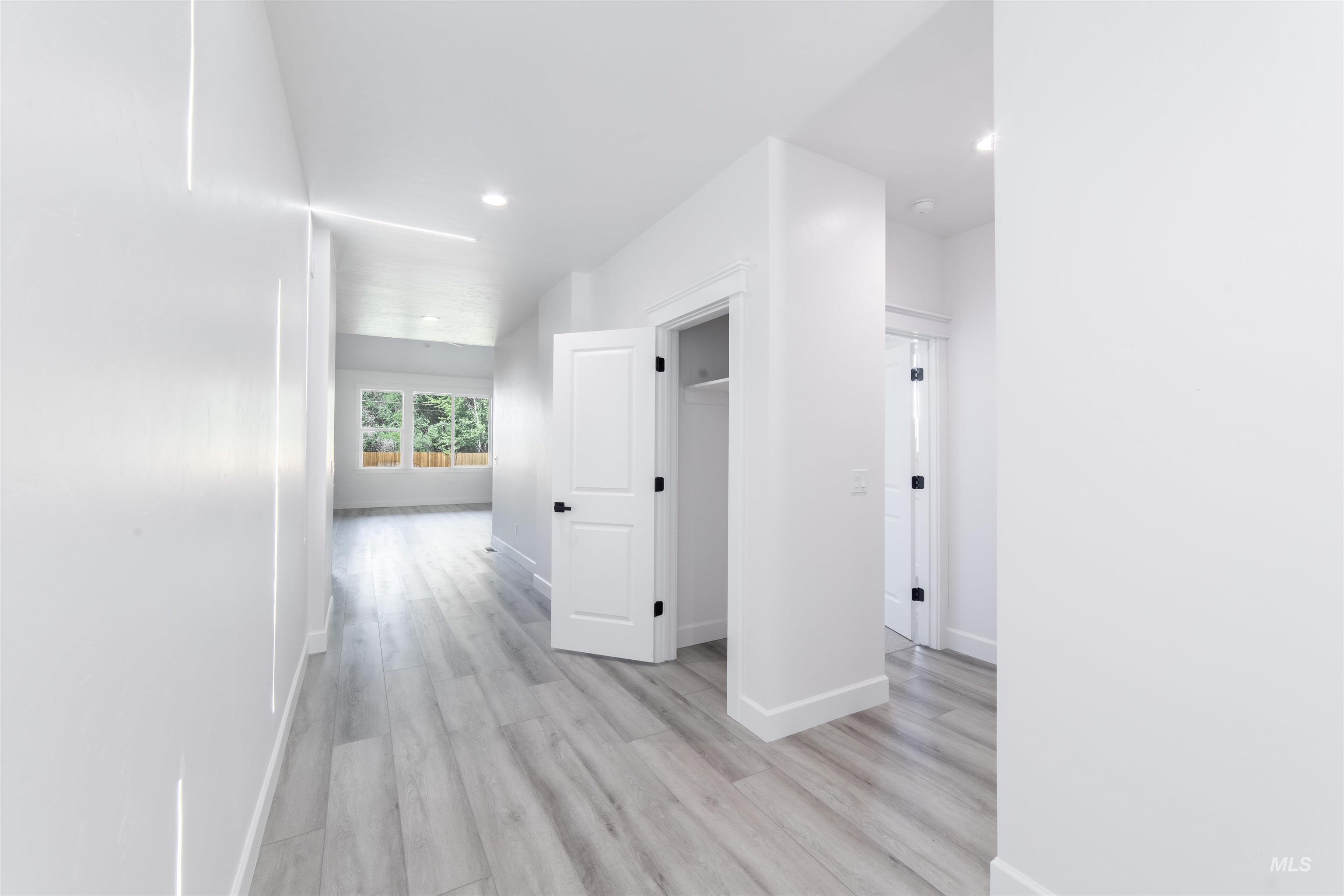Hallway with light wood-type flooring and recessed lighting