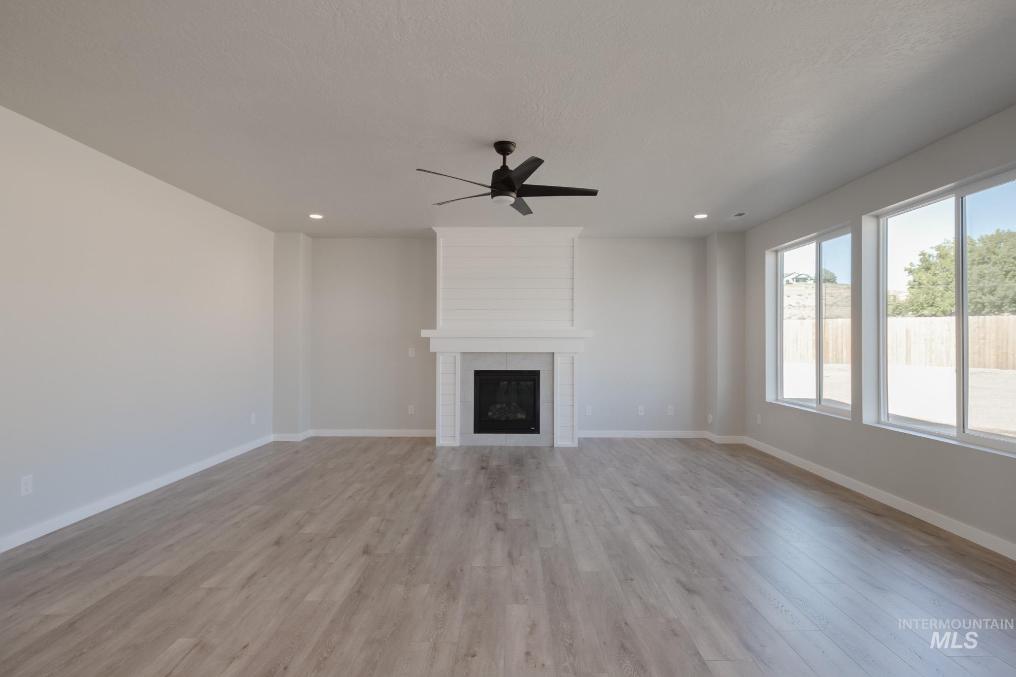 Unfurnished living room with a large fireplace, light wood-style floors, ceiling fan, and recessed lighting