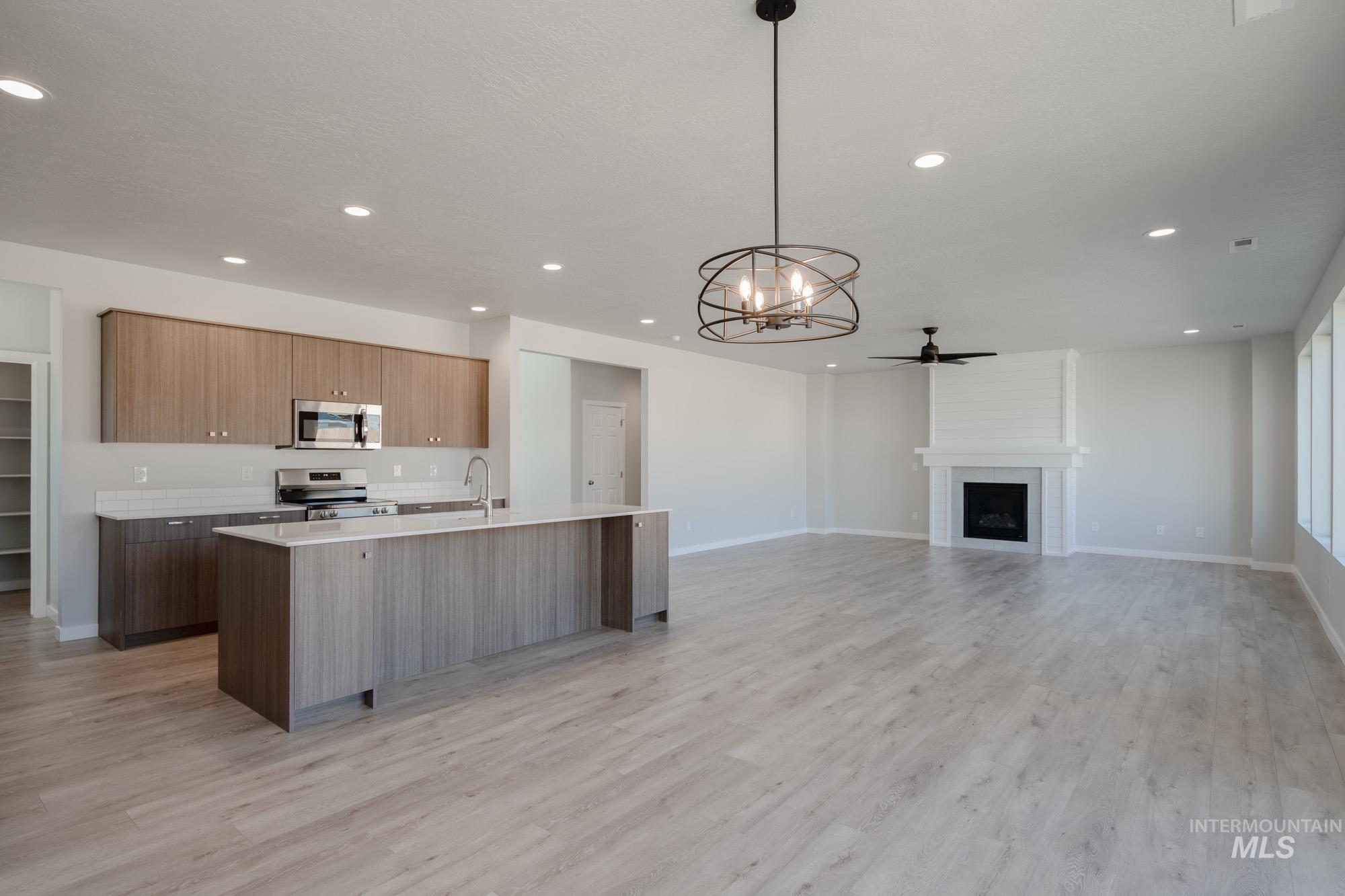 Kitchen featuring a chandelier, an island with sink, pendant lighting, appliances with stainless steel finishes, and modern cabinets