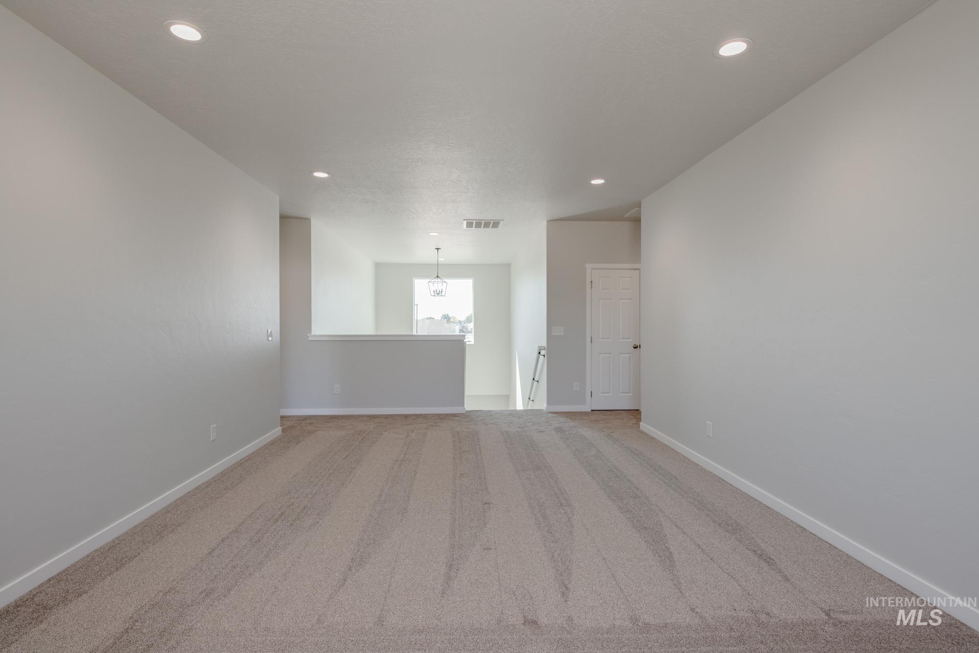 Carpeted spare room featuring recessed lighting and a chandelier