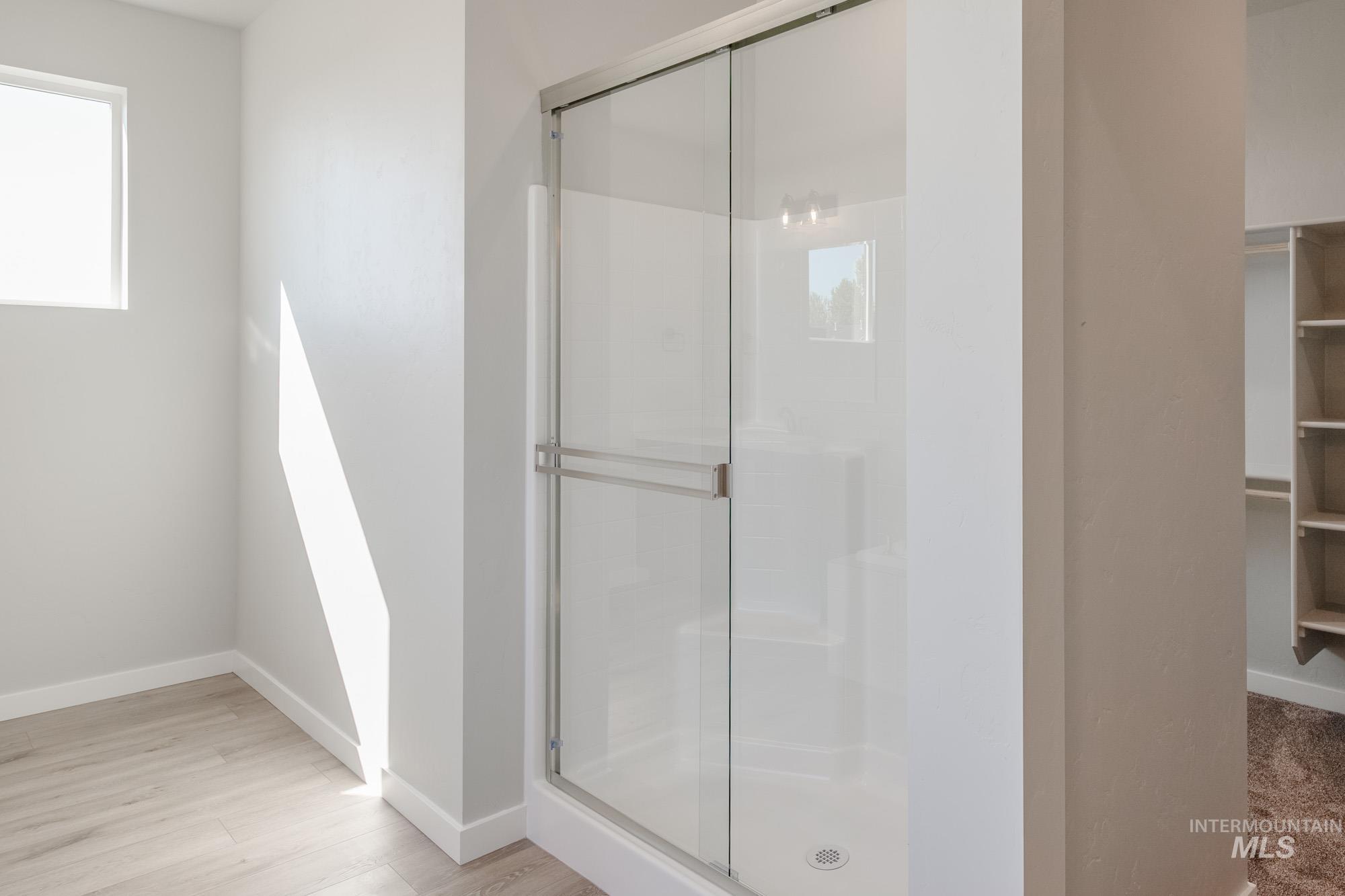 Bathroom with a stall shower, a walk in closet, and light wood finished floors