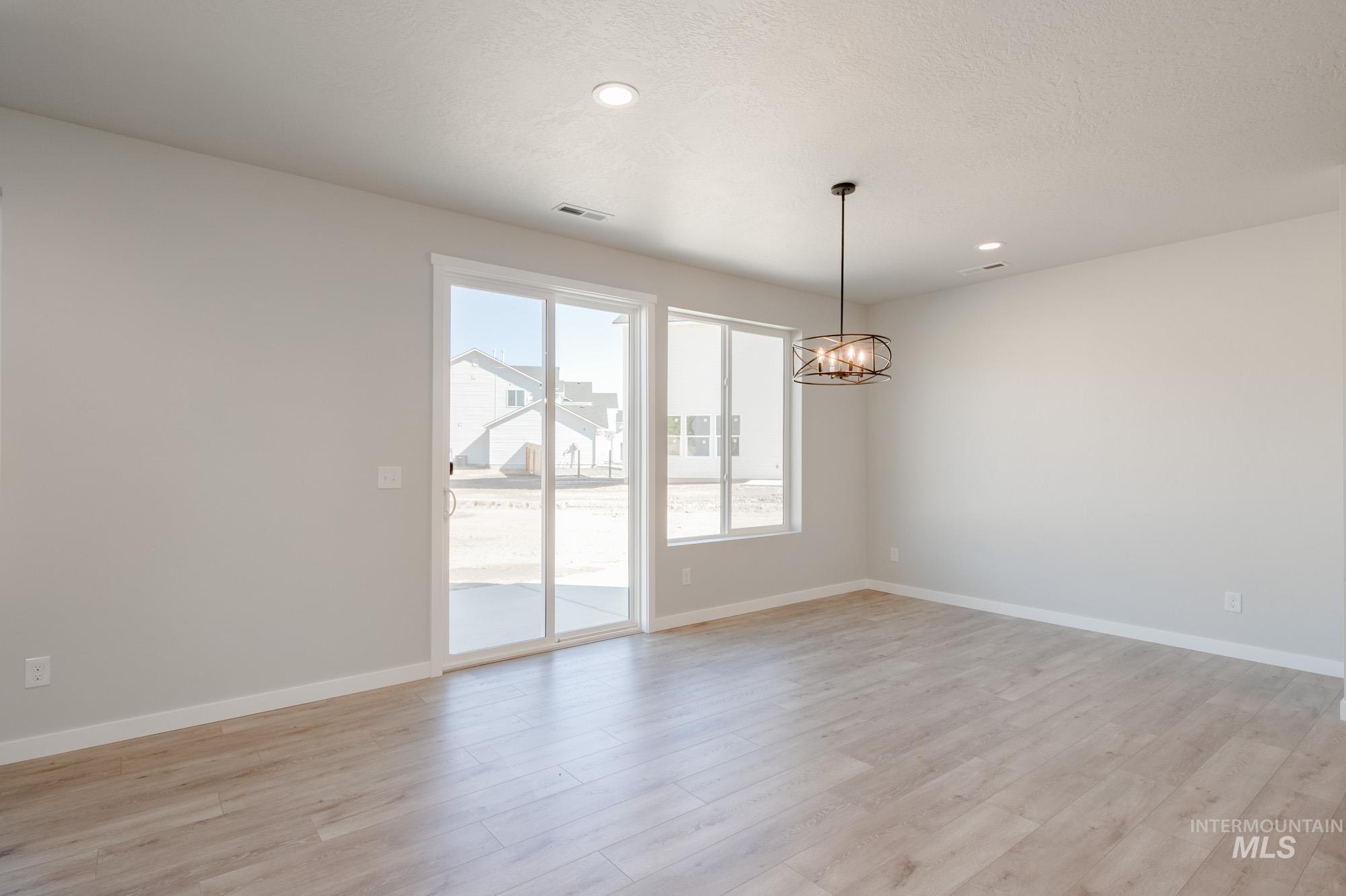 Spare room with light wood-style flooring, a chandelier, and recessed lighting