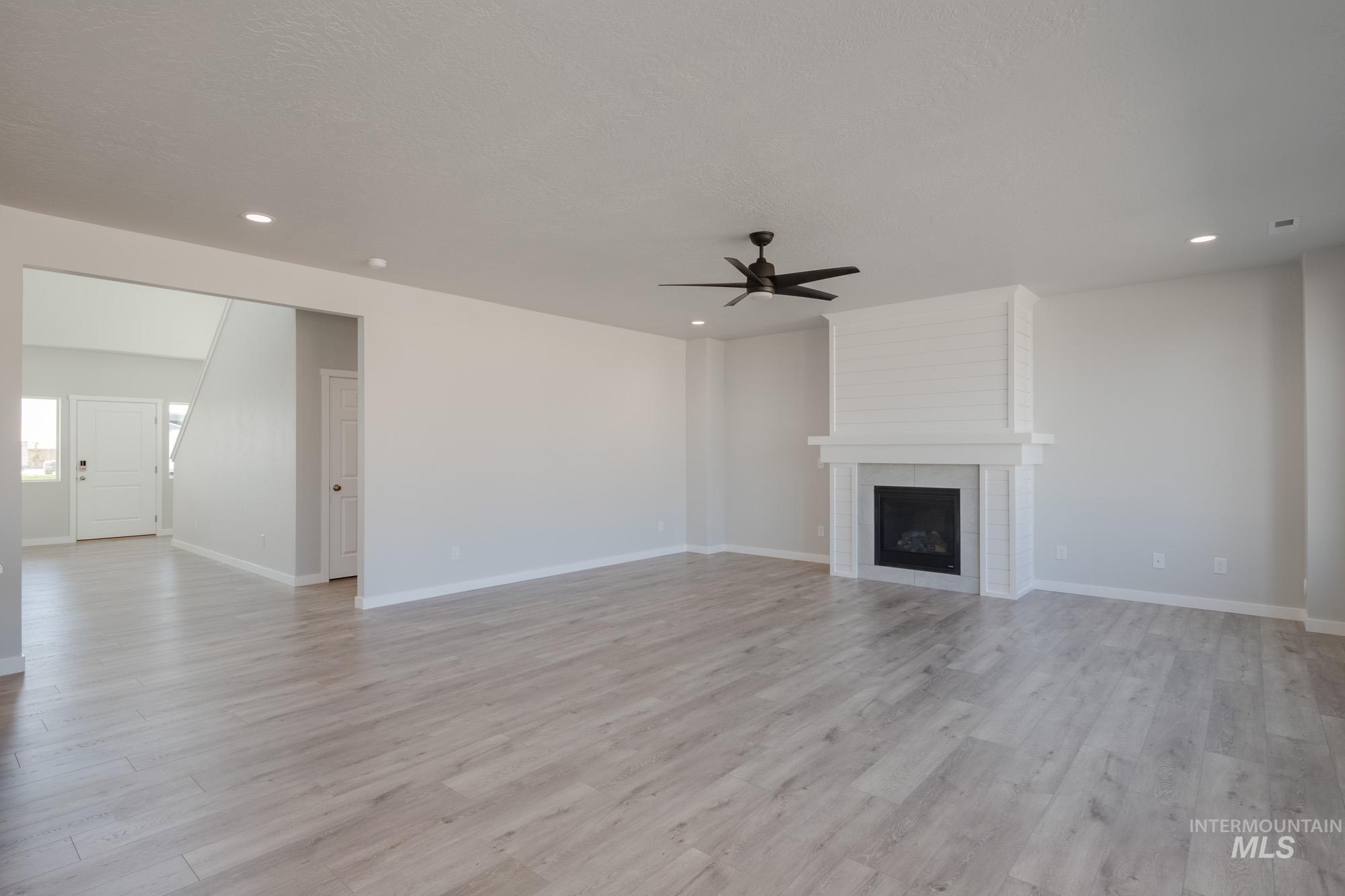 Unfurnished living room featuring light wood-type flooring, a large fireplace, recessed lighting, and ceiling fan
