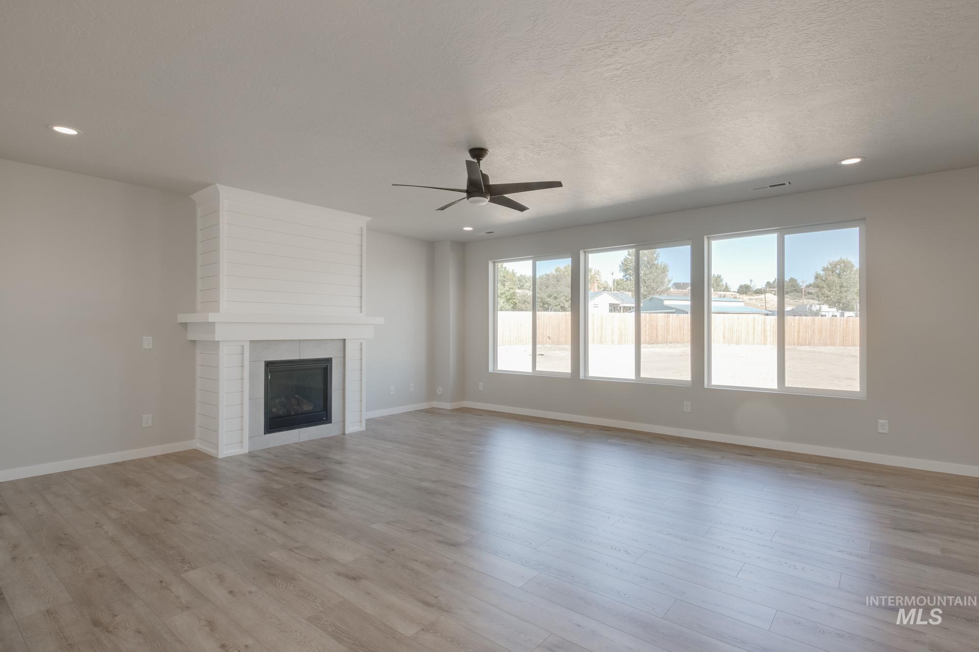 Unfurnished living room with a fireplace, ceiling fan, light wood-type flooring, and recessed lighting