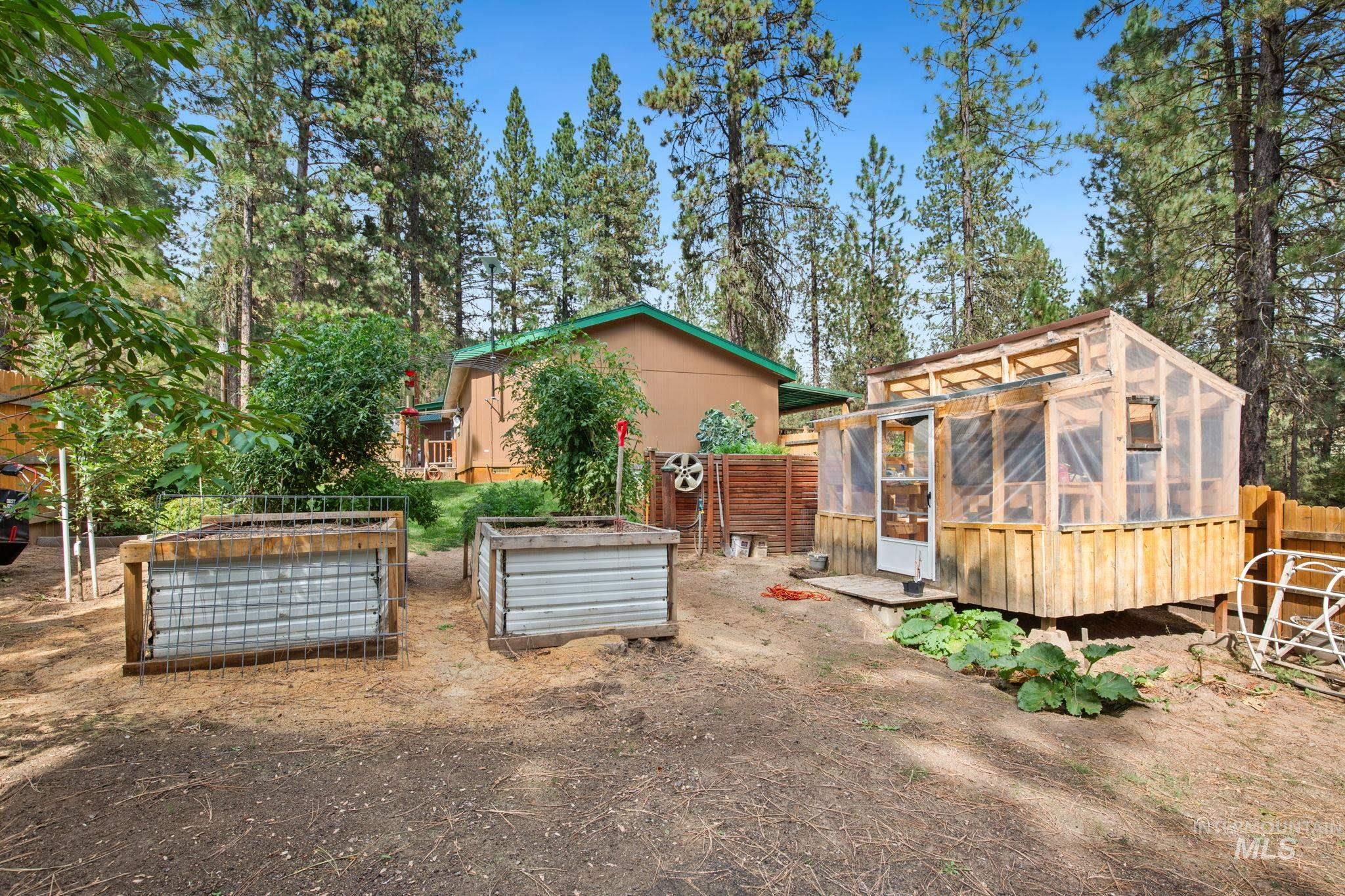 View of yard featuring a sunroom, an outdoor structure, an exterior structure, and a garden