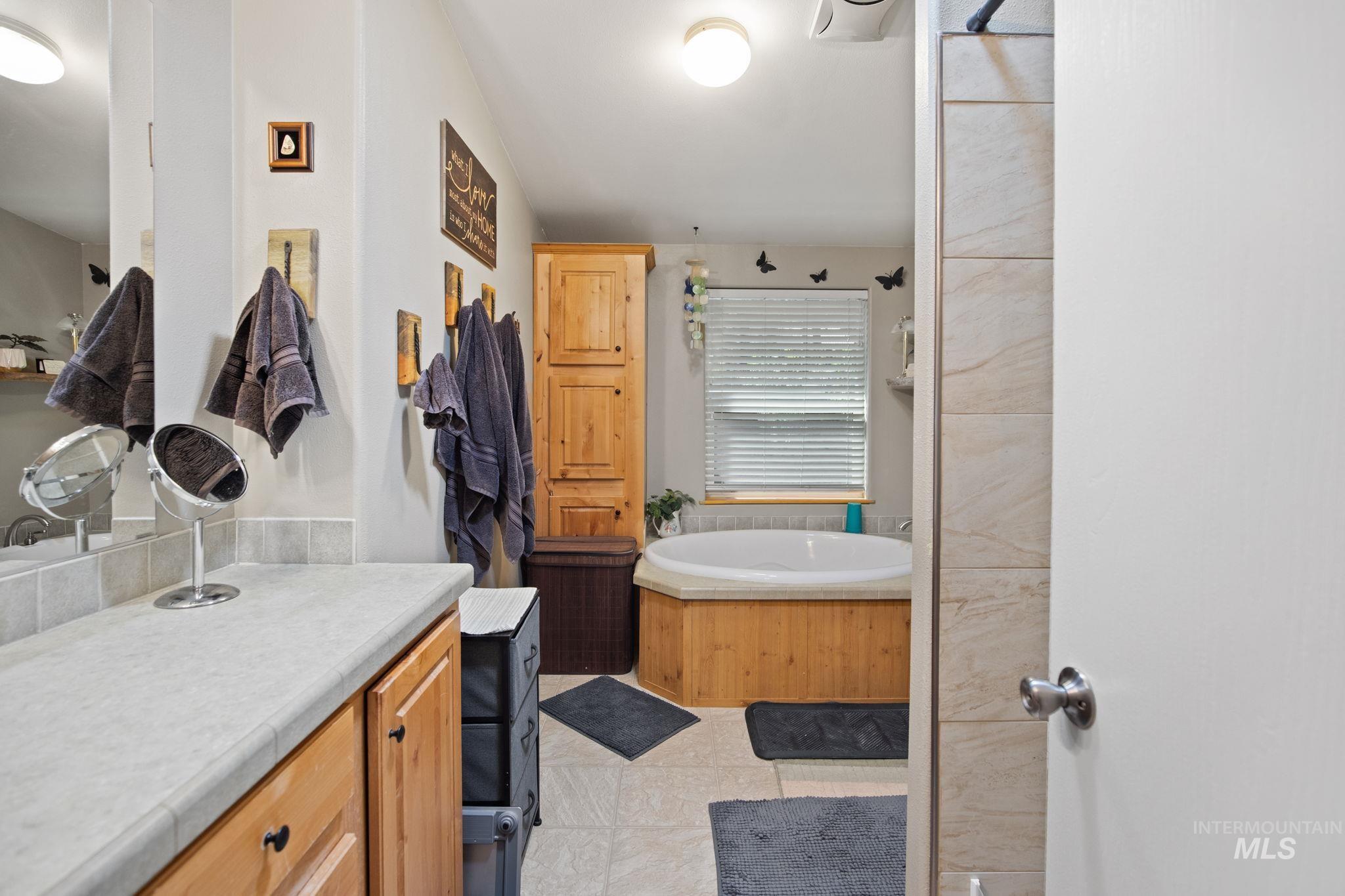 Bathroom featuring vanity, a bath, and light tile patterned flooring