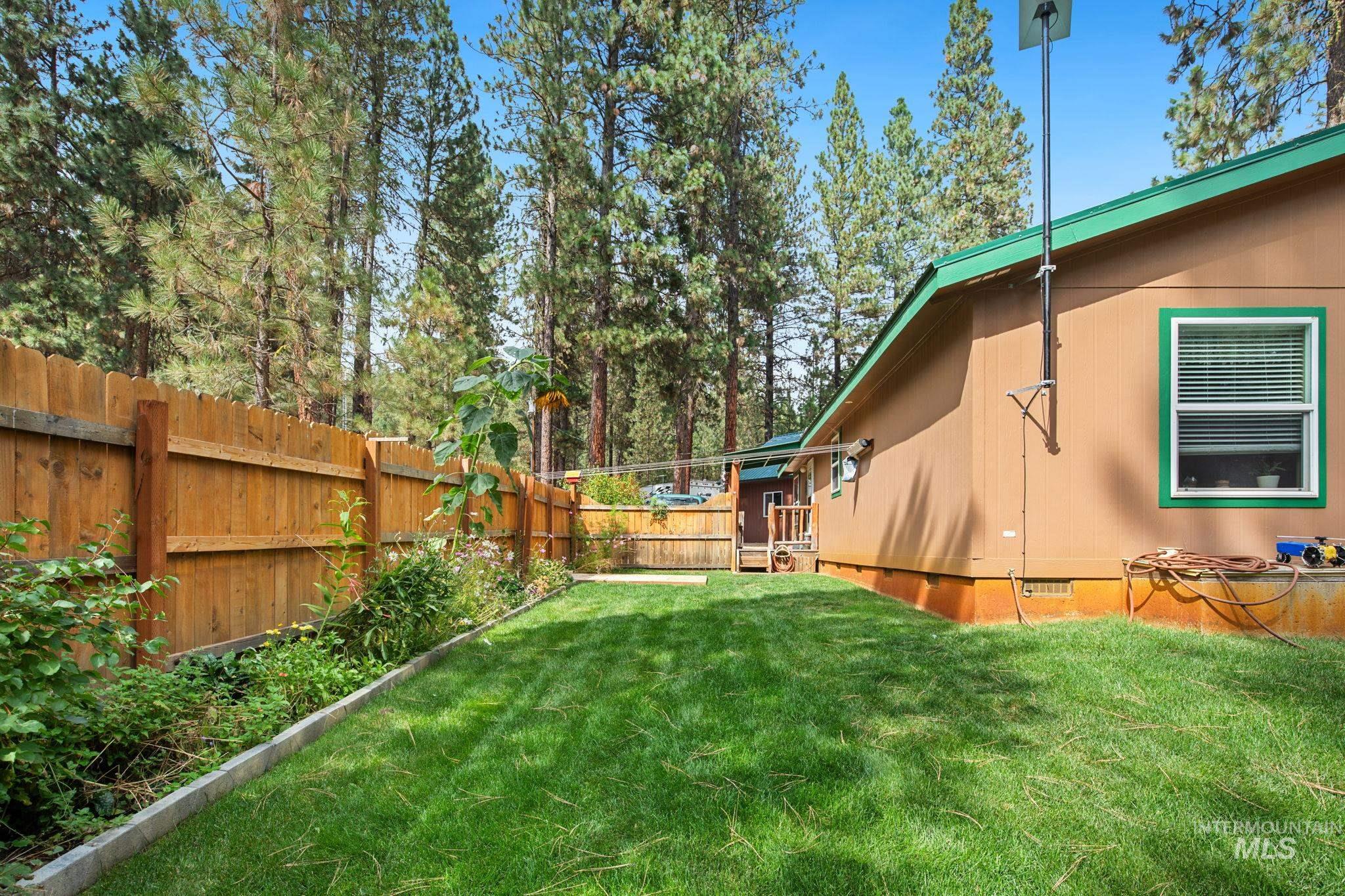 Fenced backyard with view of wooded area