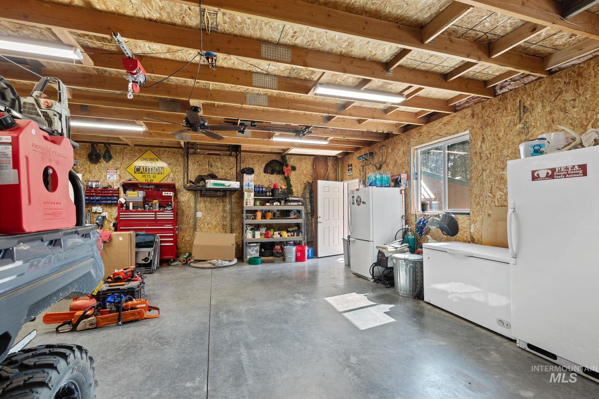 Garage featuring white fridge, freestanding refrigerator, and a workshop area